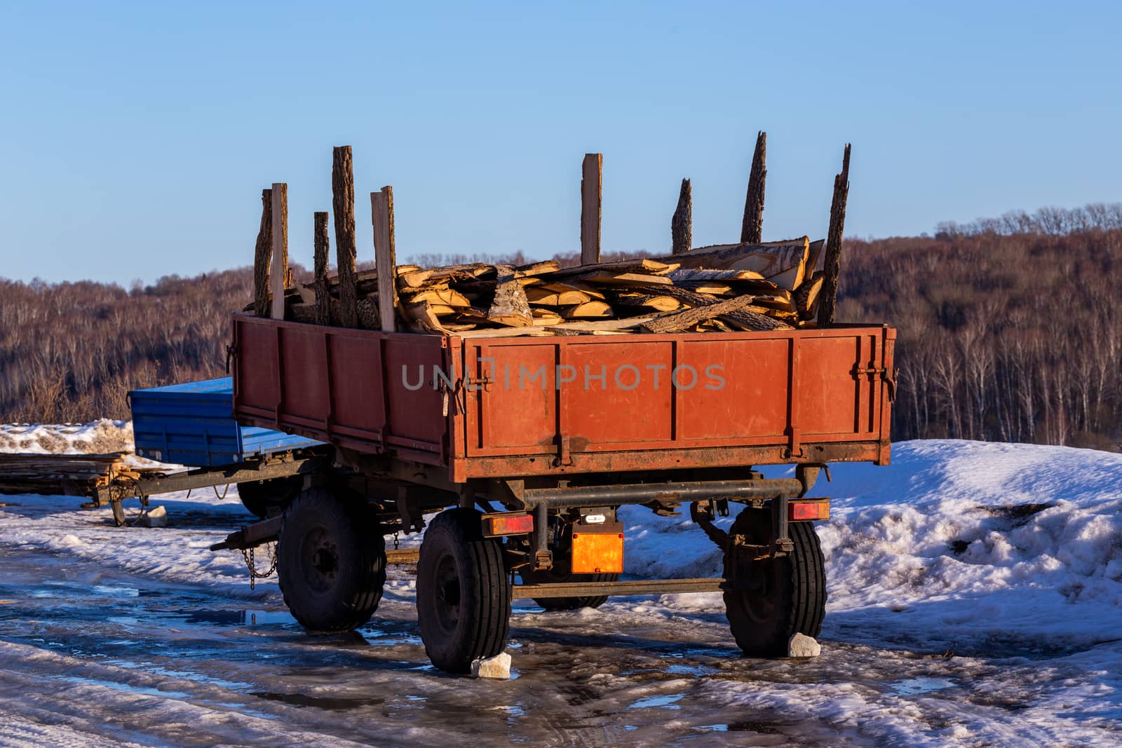 old rustic trailer with firewood lumber leftovers at winter daylight with selective focus