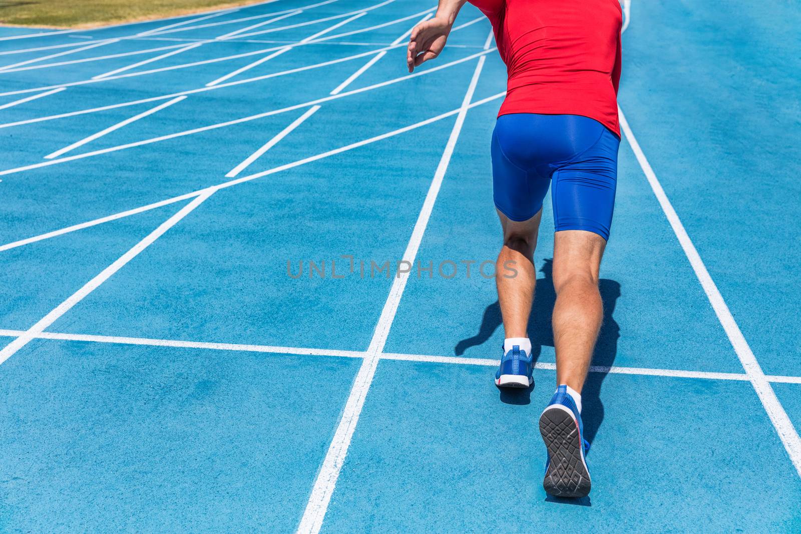 Runner athlete starting running at start of run track on blue running tracks at outdoor athletics and fiel stadium. Sprinter. Sport and fitness man lower body, legs and running shoes sprinting.