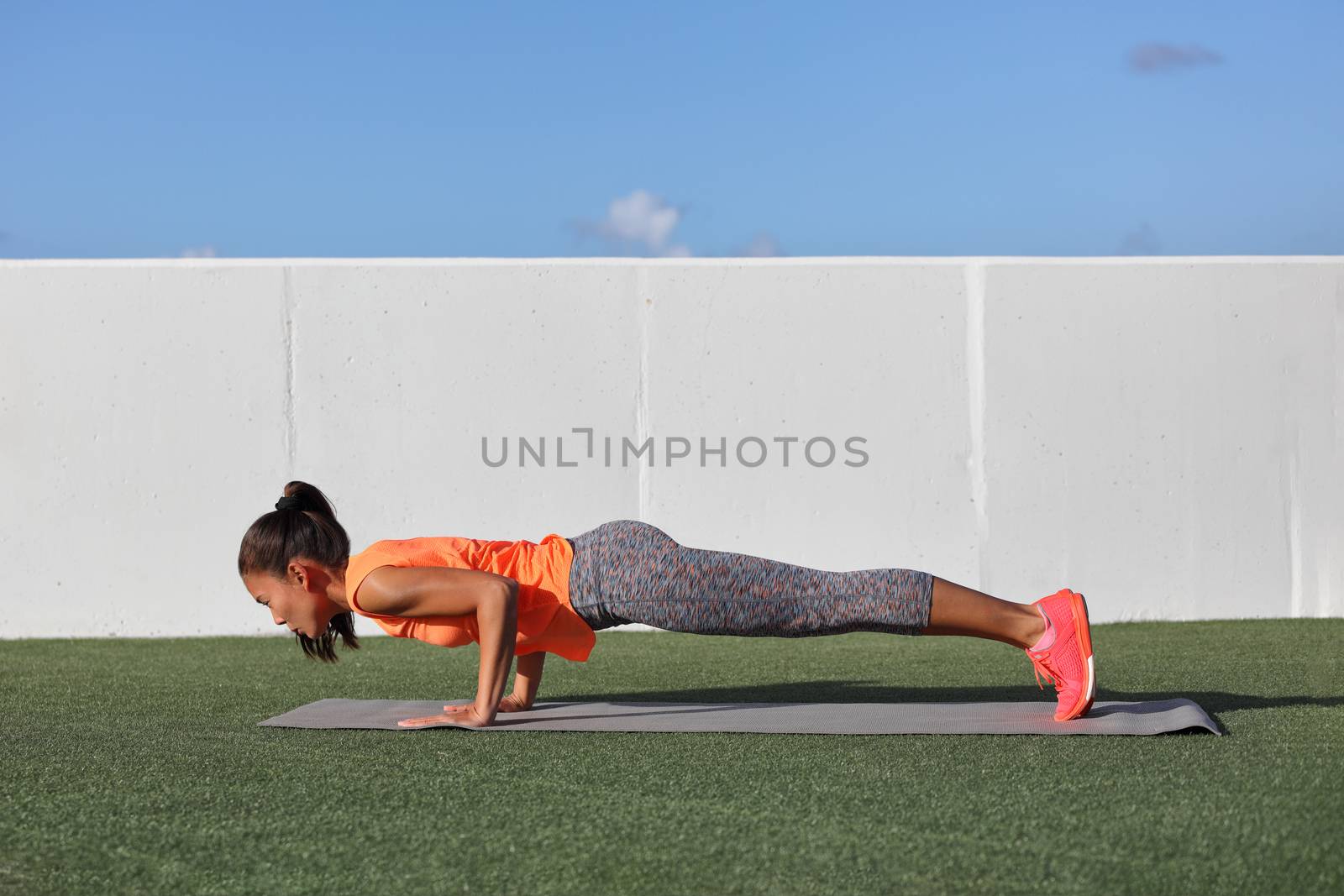 Yoga fitness woman practicing chaturanga pose push ups or press up on exercise mat at outdoor home. Fit and healthy young girl doing morning core body workout push up strength training. by Maridav