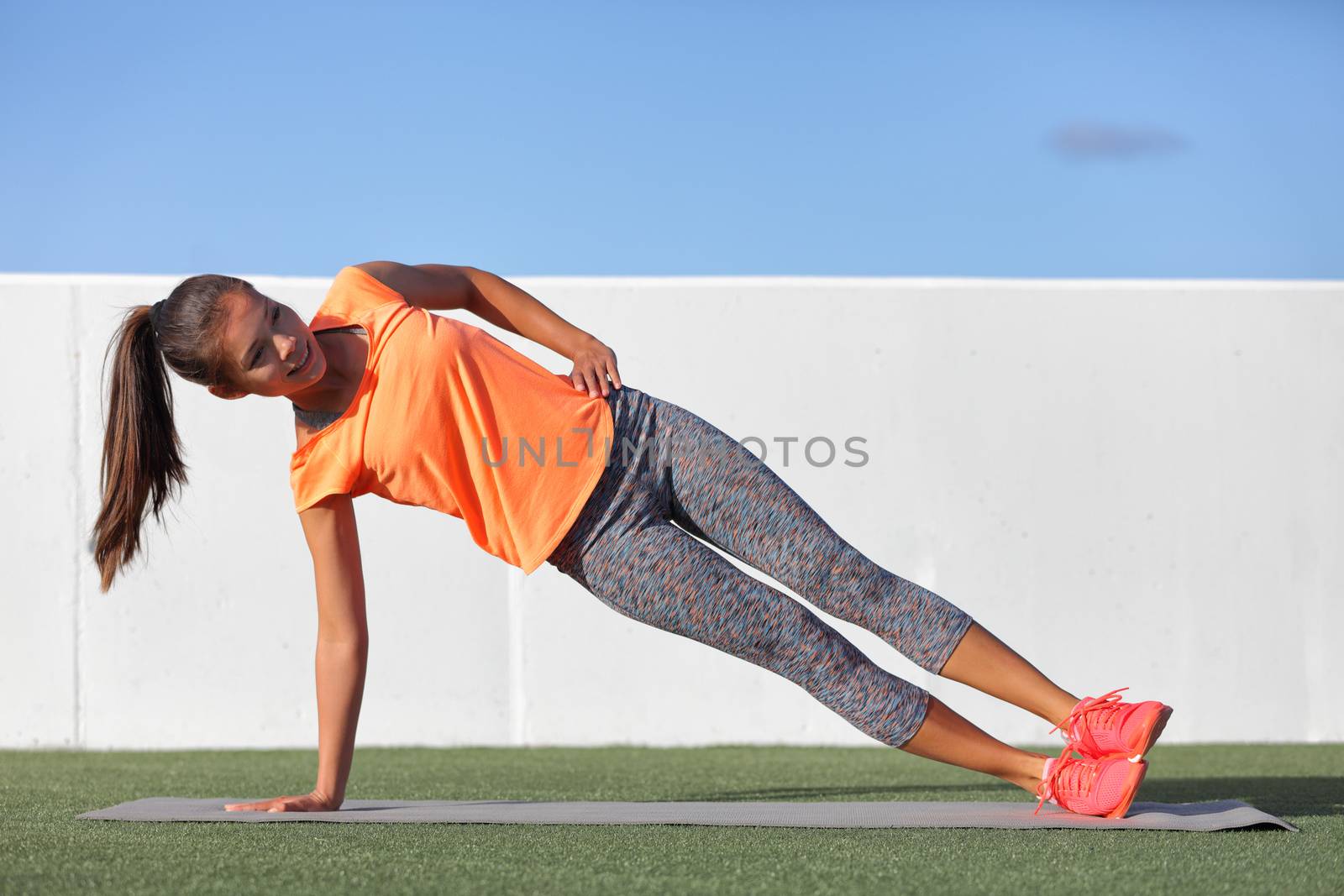 Side plank fitness woman training body core planking exercise. Workout at outdoor gym or home garden Asian girl exercising obliques abs muscles with yoga pose plank.