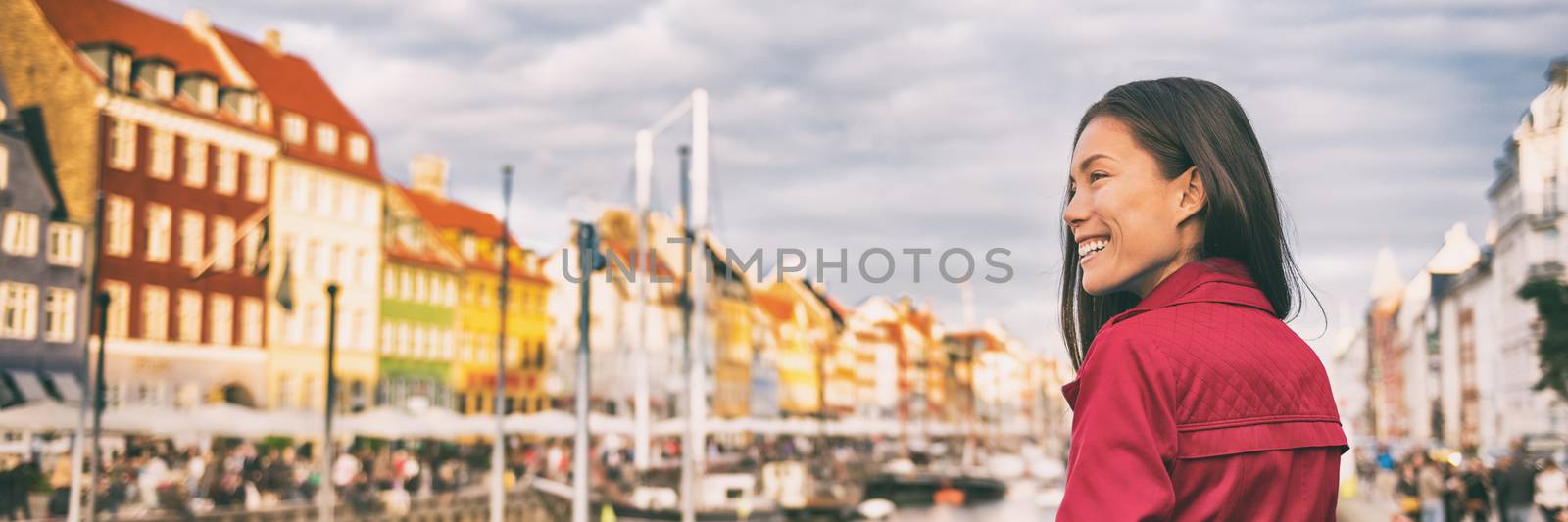 Happy Asian woman walking in Copenhagen city street. Denmark spring travel tourist visiting Nyhavn famous attraction, old water canal banner.