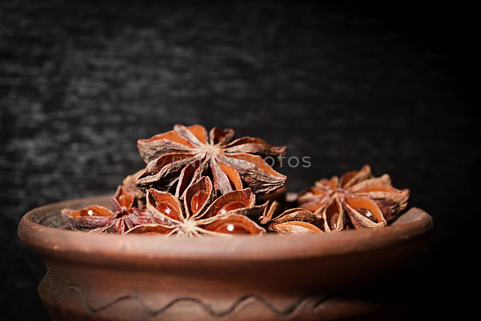 Anis in bowl, dark background, selective focus