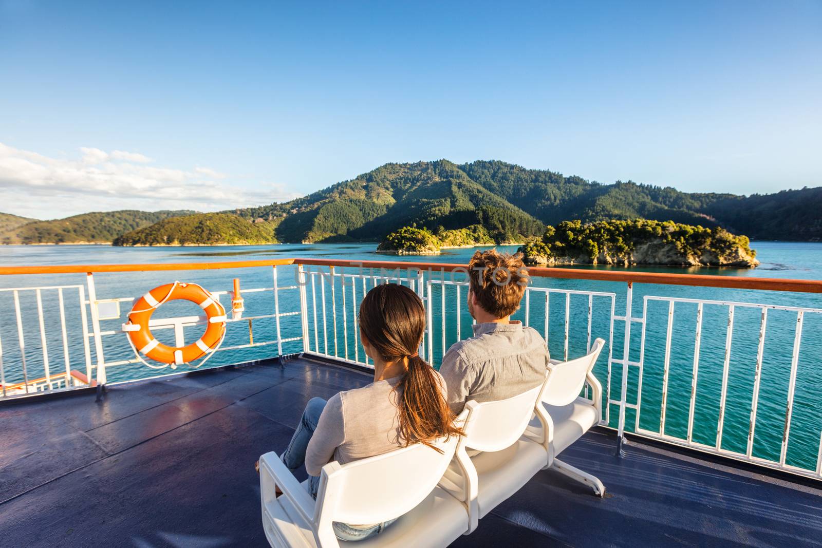 New Zealand cruise travel passengers enjoying nature view of ferry boat cruising in Marlborough sounds trip from Picton to Wellington, Cook strait. Couple tourists sitting outside on deck. by Maridav