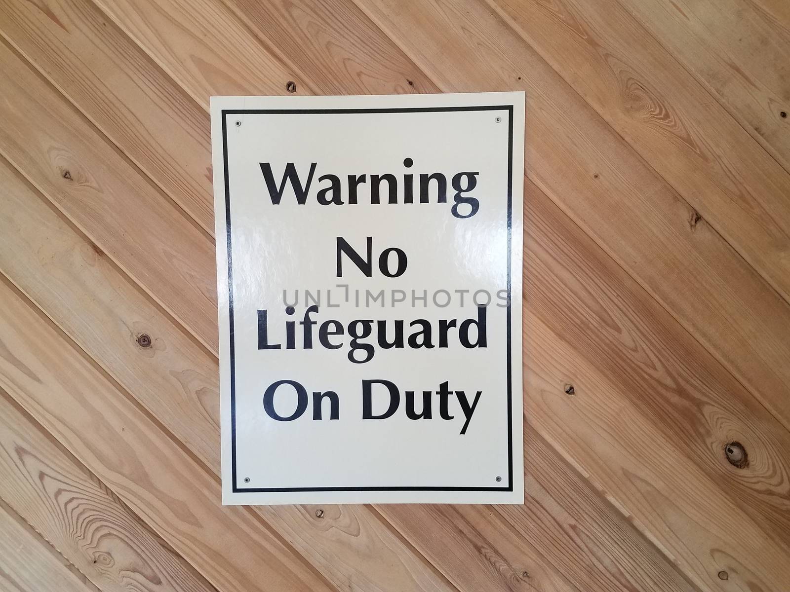 white warning no lifeguard on duty sign on wood wall