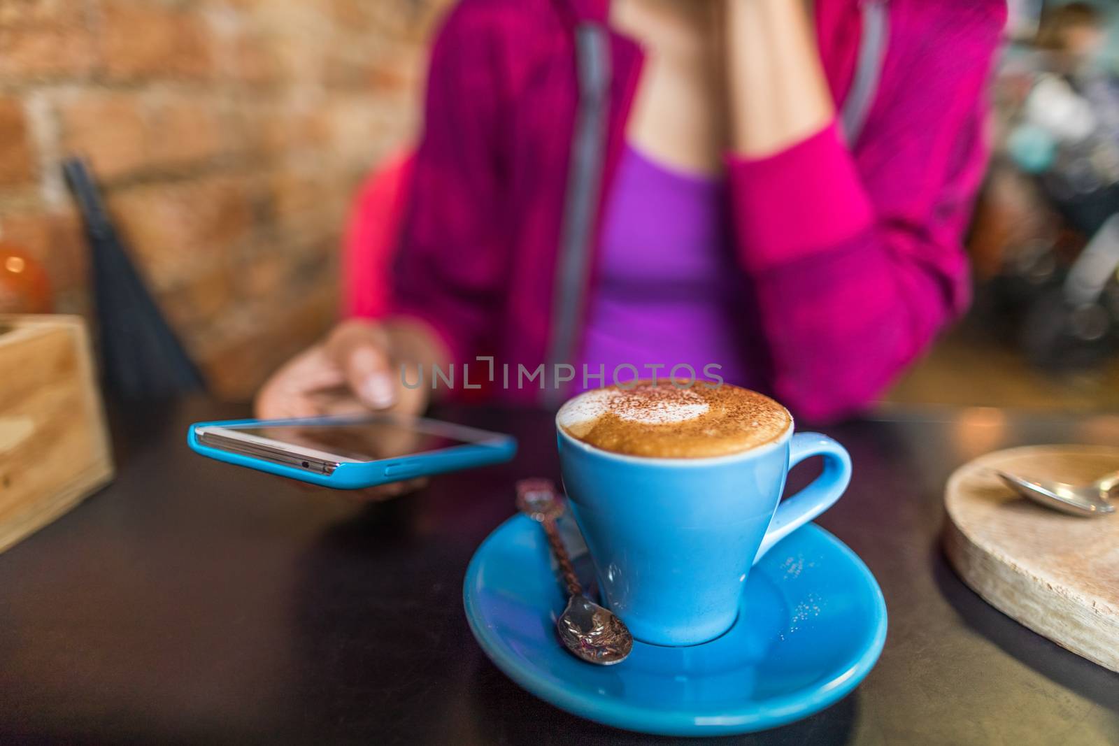 Cafe woman drinking cappuccino coffee cup using mobile phone app. Urban lifestyle young people addicted to social media online.