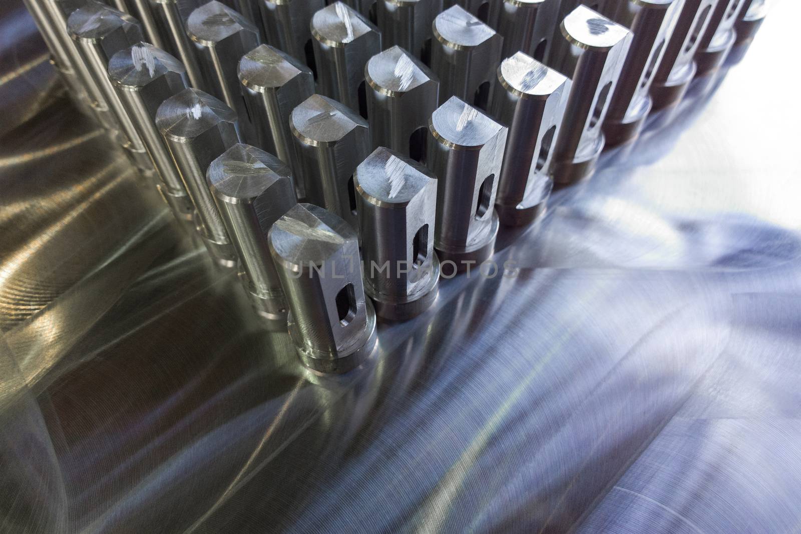 Batch of shiny metal parts after cnc turning and milling on flat milled surface with selective focus