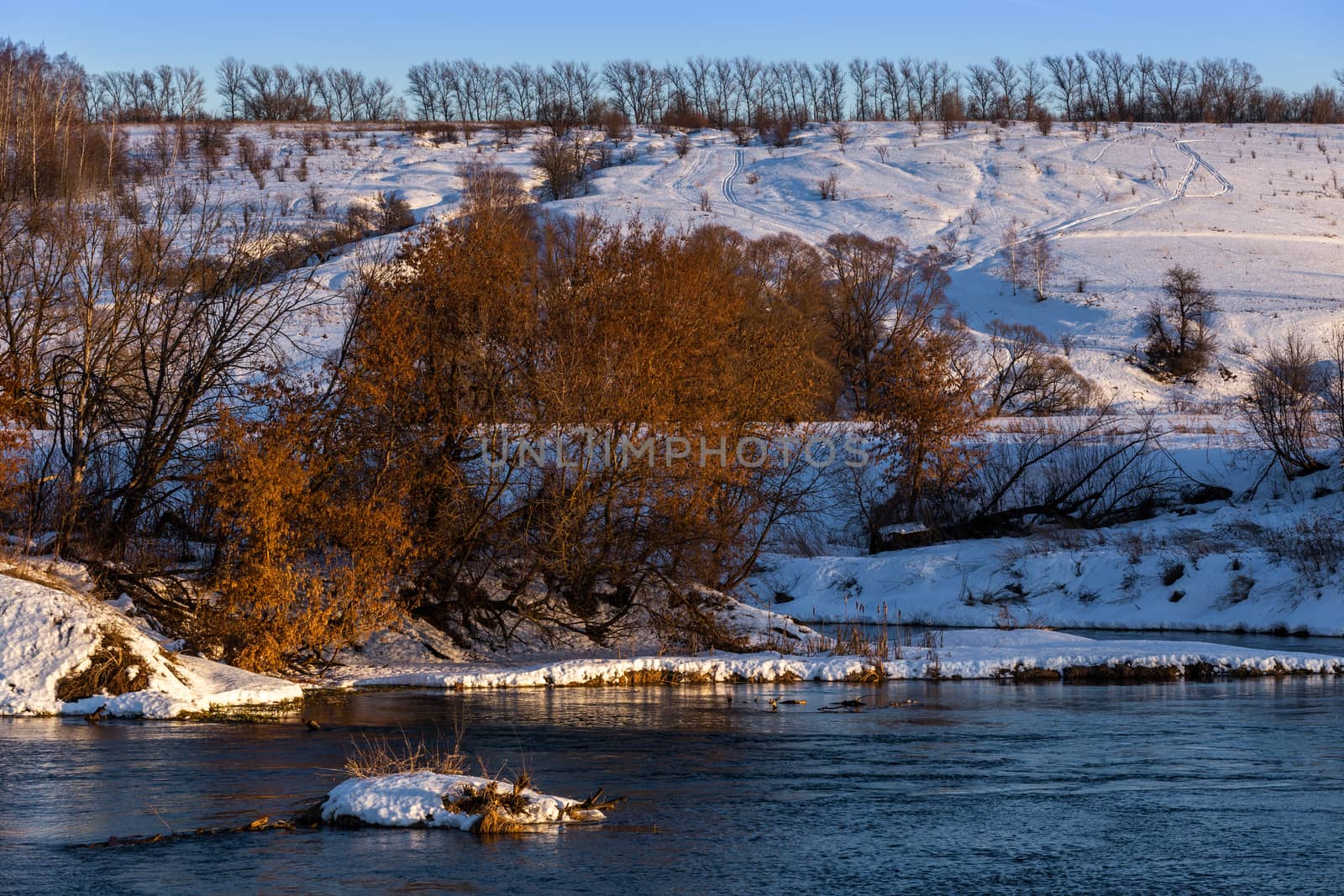 amateur winter riverside landscape with birch forest and slope.