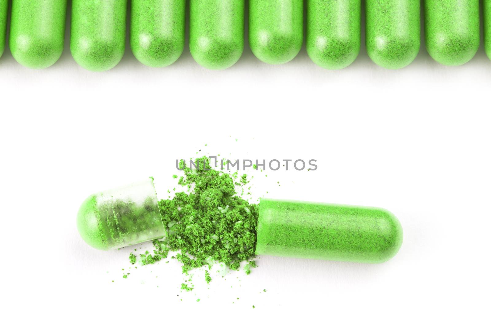 row of ufo green color organic capsules isolated on white background closeup with one opened.