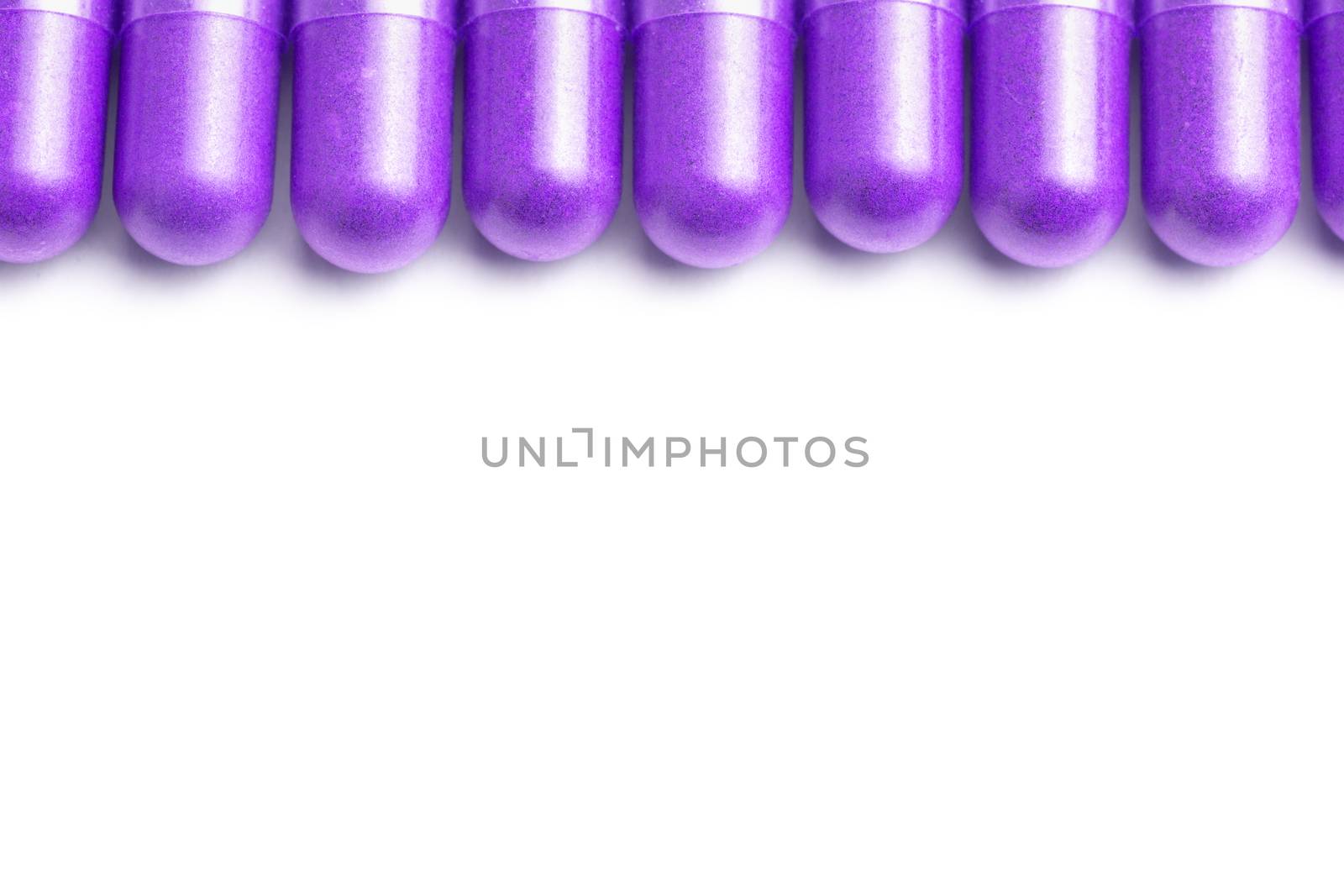 row of proton purple color organic capsules isolated on white background closeup with selective focus.
