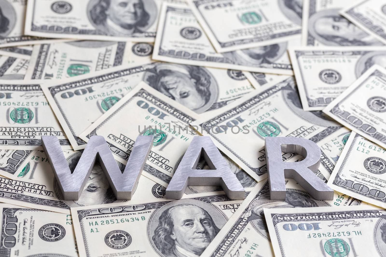 The word WAR laid with metal letters on the US dollar banknotes mosaic - close shot with selective focus