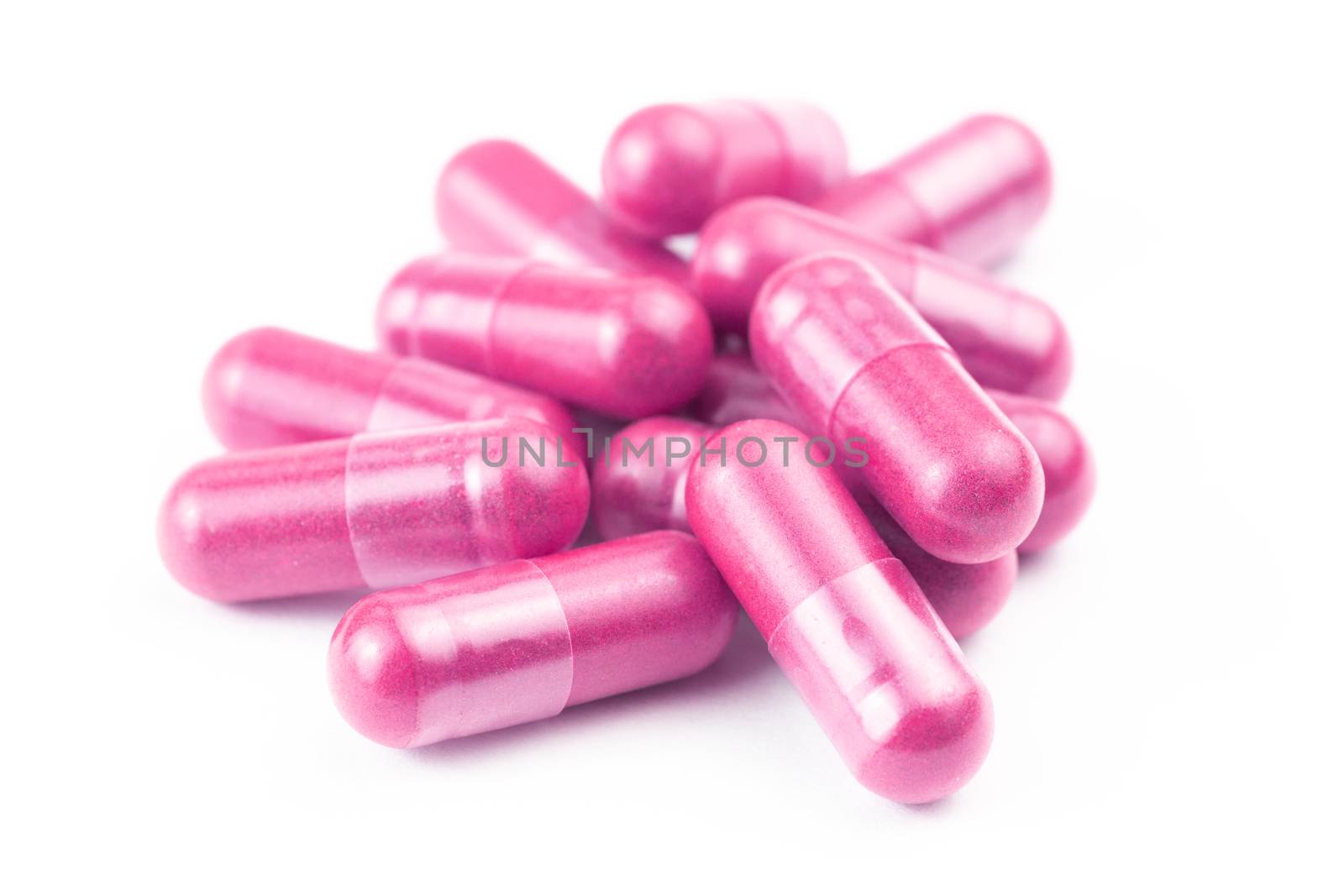 pile of pink organic capsules isolated on white background closeup with selective focus.