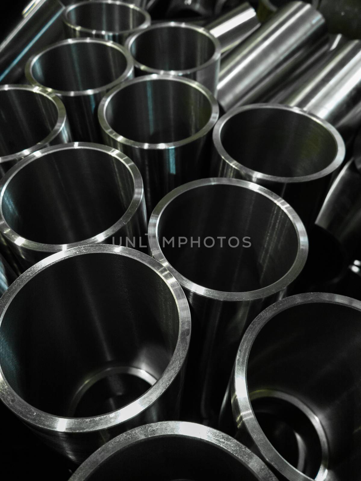 dark industrial background with cnc machined shiny steel pipes - selective focus and lens blur technique