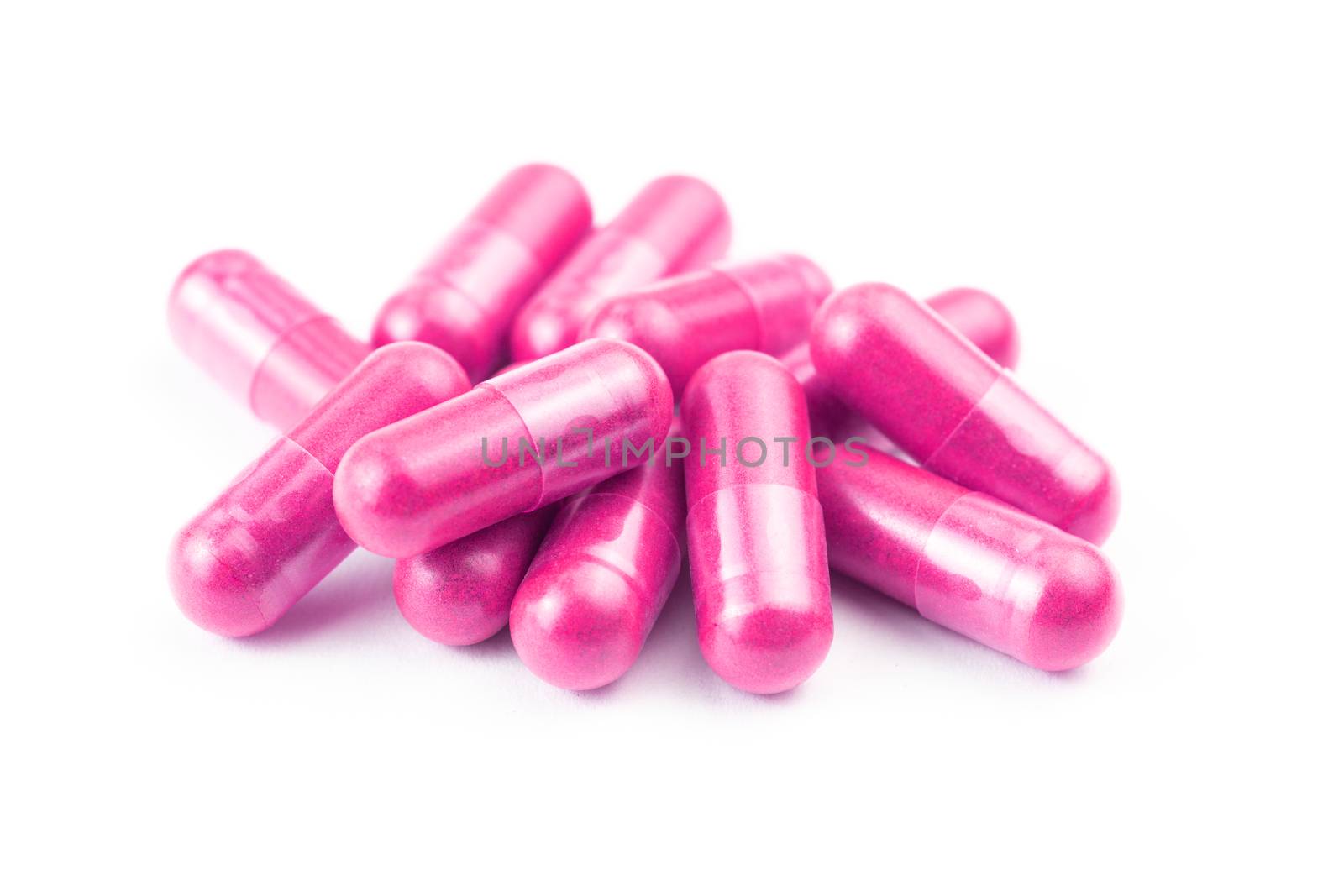 pile of pink organic capsules isolated on white background closeup with selective focus.