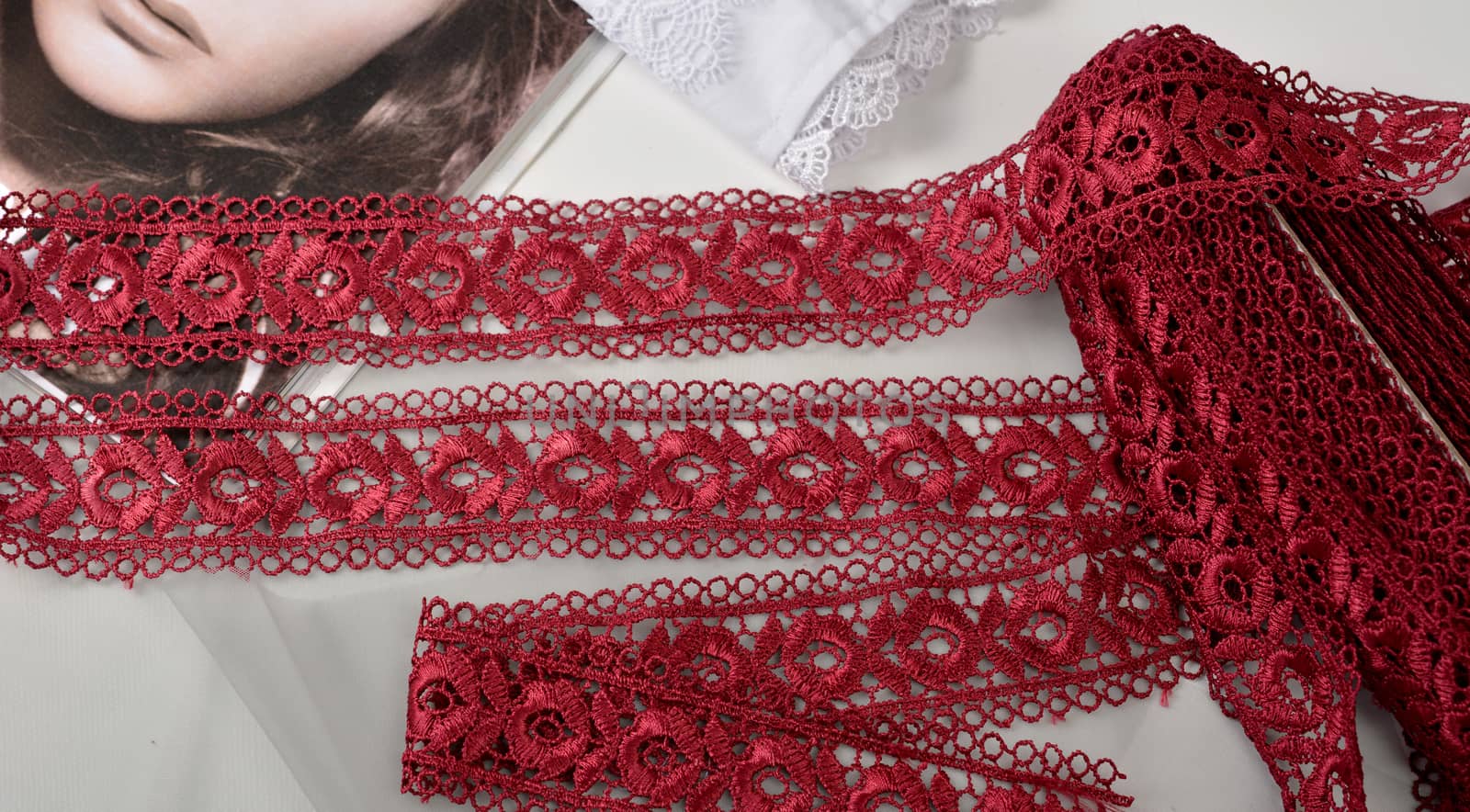 Tapes of red vinous gentle guipure, beauty lace fabric on light background by polyats