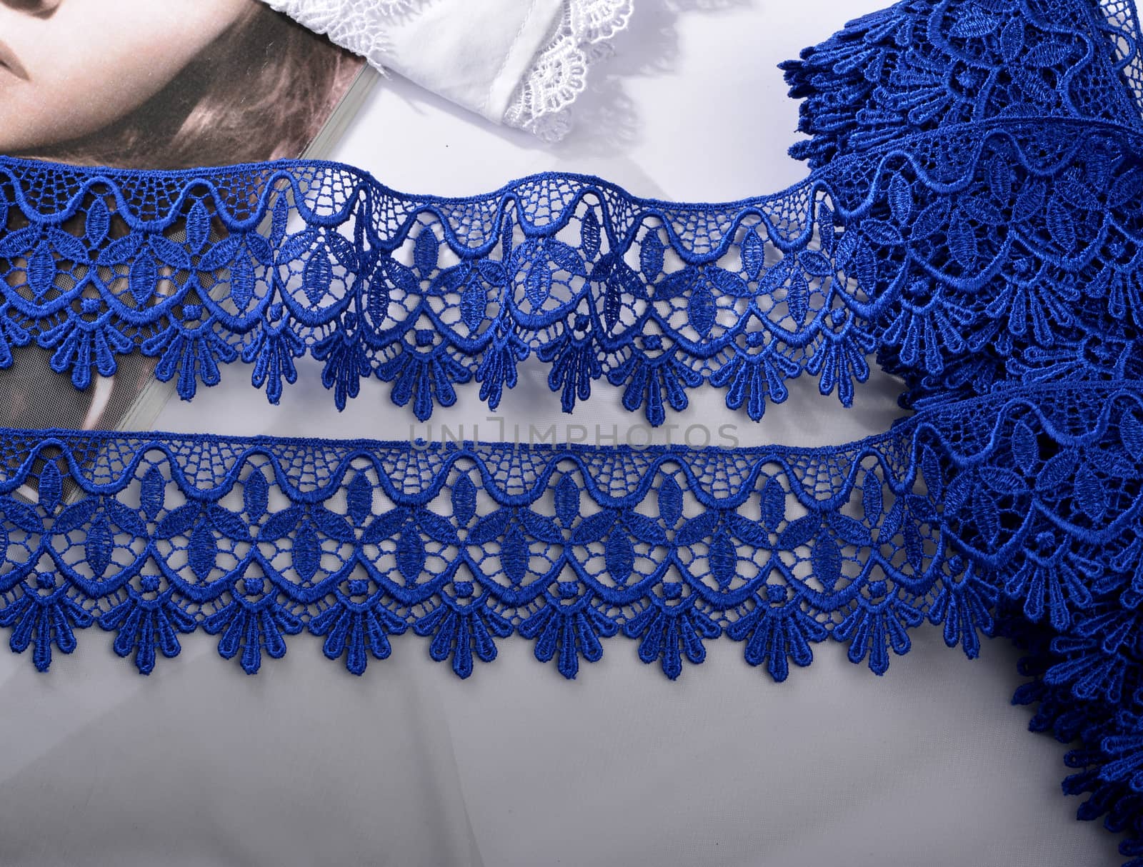 Tapes of blue gentle guipure, beauty silk lace fabric on light background. Elastic material. Using for Atelier and needlework store. Flat lay style