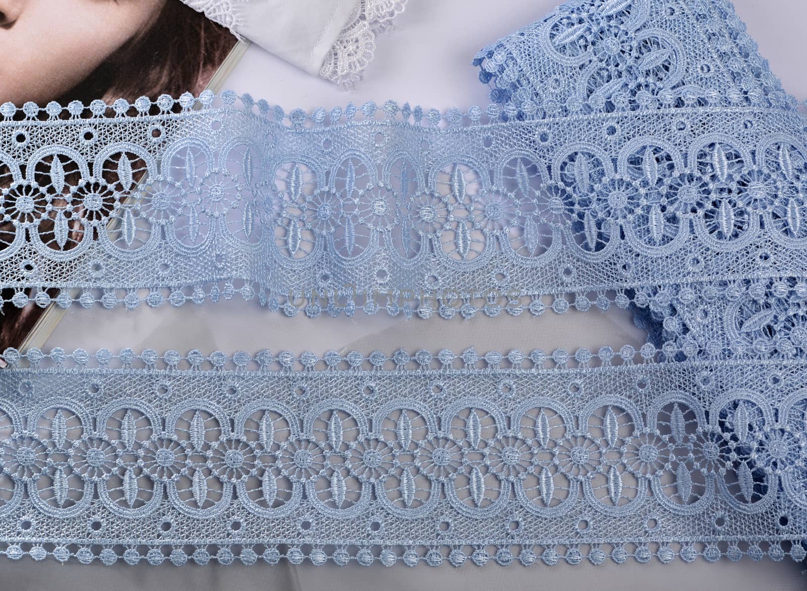 Tapes of blue gentle guipure, beauty silk lace fabric on light background. Elastic material. Using for Atelier and needlework store. Flat lay style