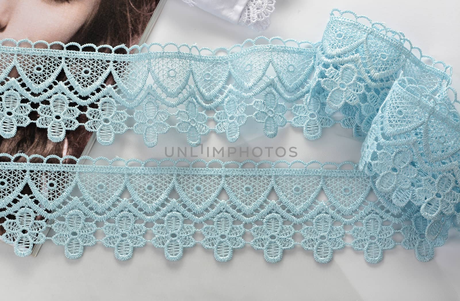 Tapes of blue gentle guipure, beauty silk lace fabric on light background. Elastic material. Using for Atelier and needlework store. Flat lay style