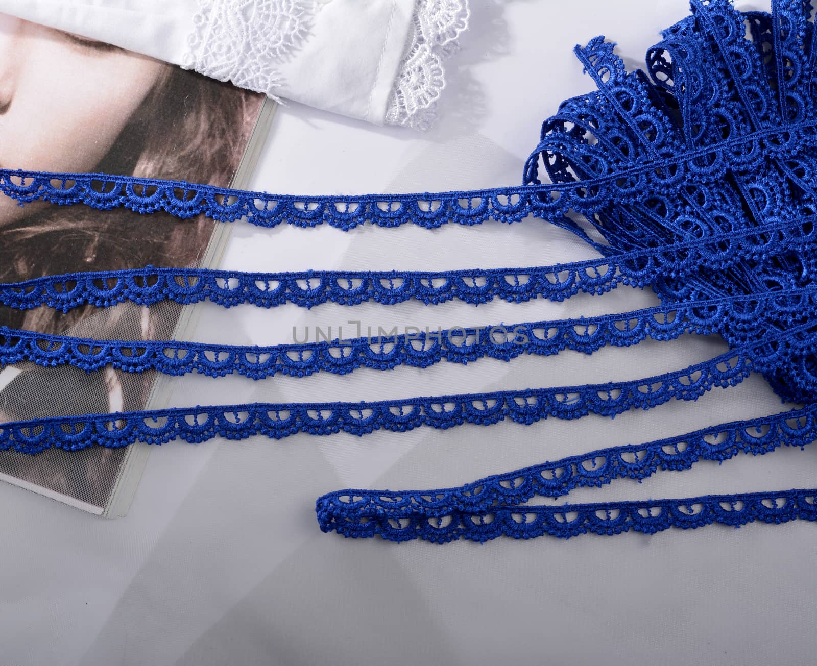 Tapes of blue gentle guipure, beauty silk lace fabric on light background. Elastic material. Using for Atelier and needlework store. Flat lay style