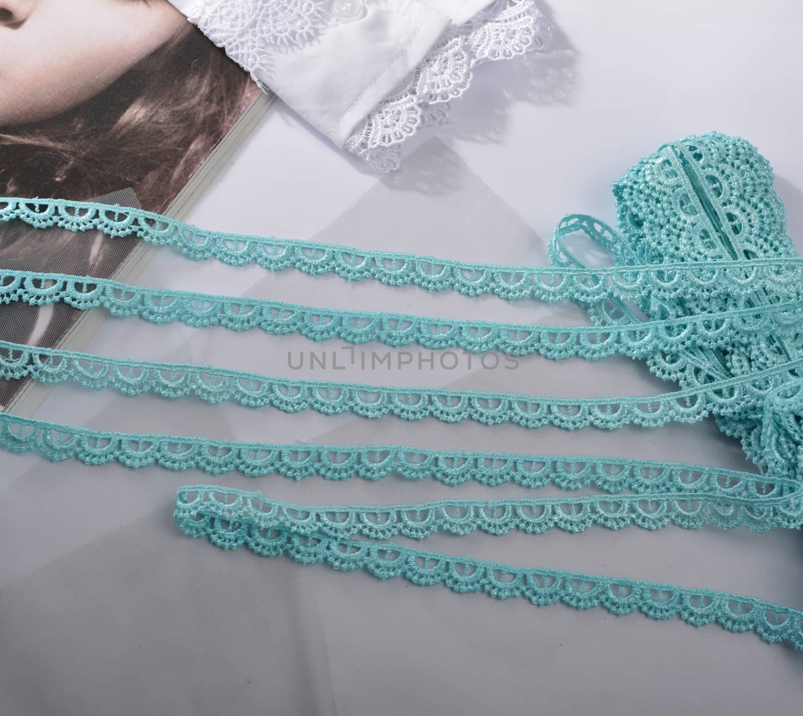 Tapes of blue gentle guipure, beauty silk lace fabric on light background. Elastic material. Using for Atelier and needlework store. Flat lay style