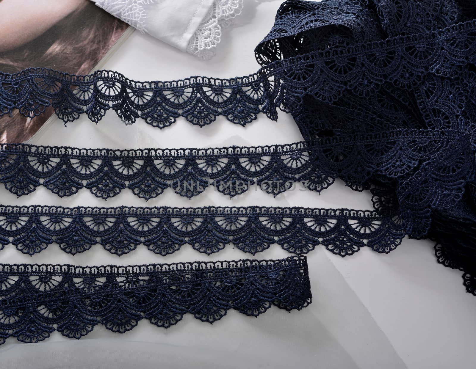 Tapes of blue gentle guipure, beauty silk lace fabric on light background. Elastic material. Using for Atelier and needlework store. Flat lay style