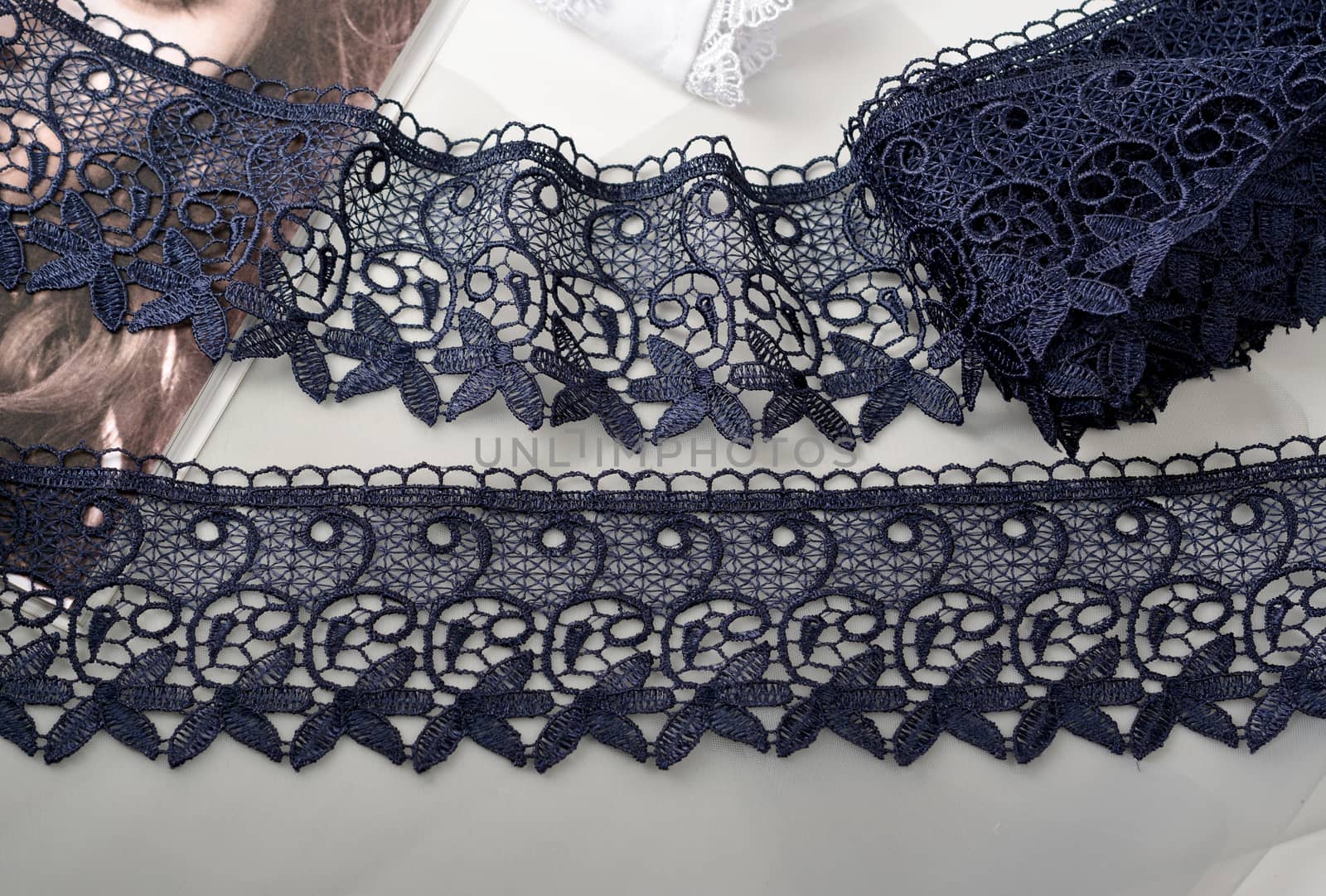 Tapes of blue gentle guipure, beauty silk lace fabric on light background. Elastic material. Using for Atelier and needlework store. Flat lay style