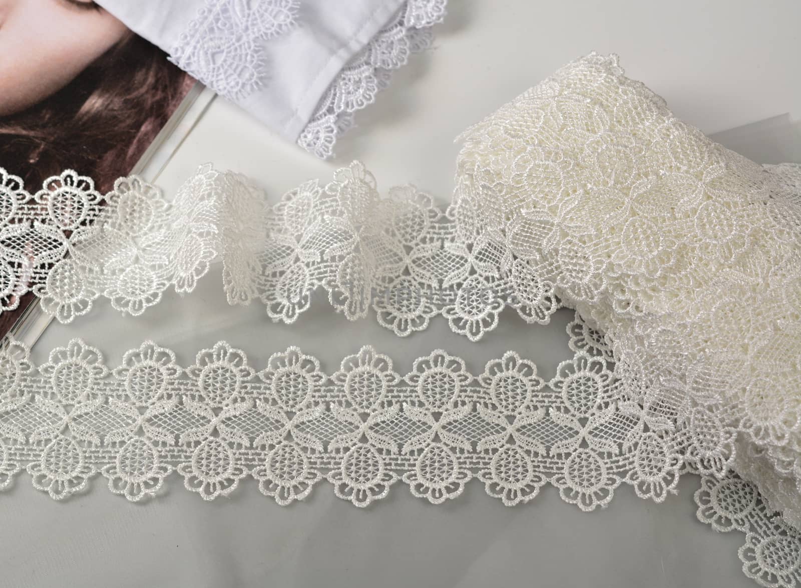 Tapes of ecru white guipure, beauty silk lace fabric on light background. Elastic material. Using for Atelier and needlework store. Flat lay style