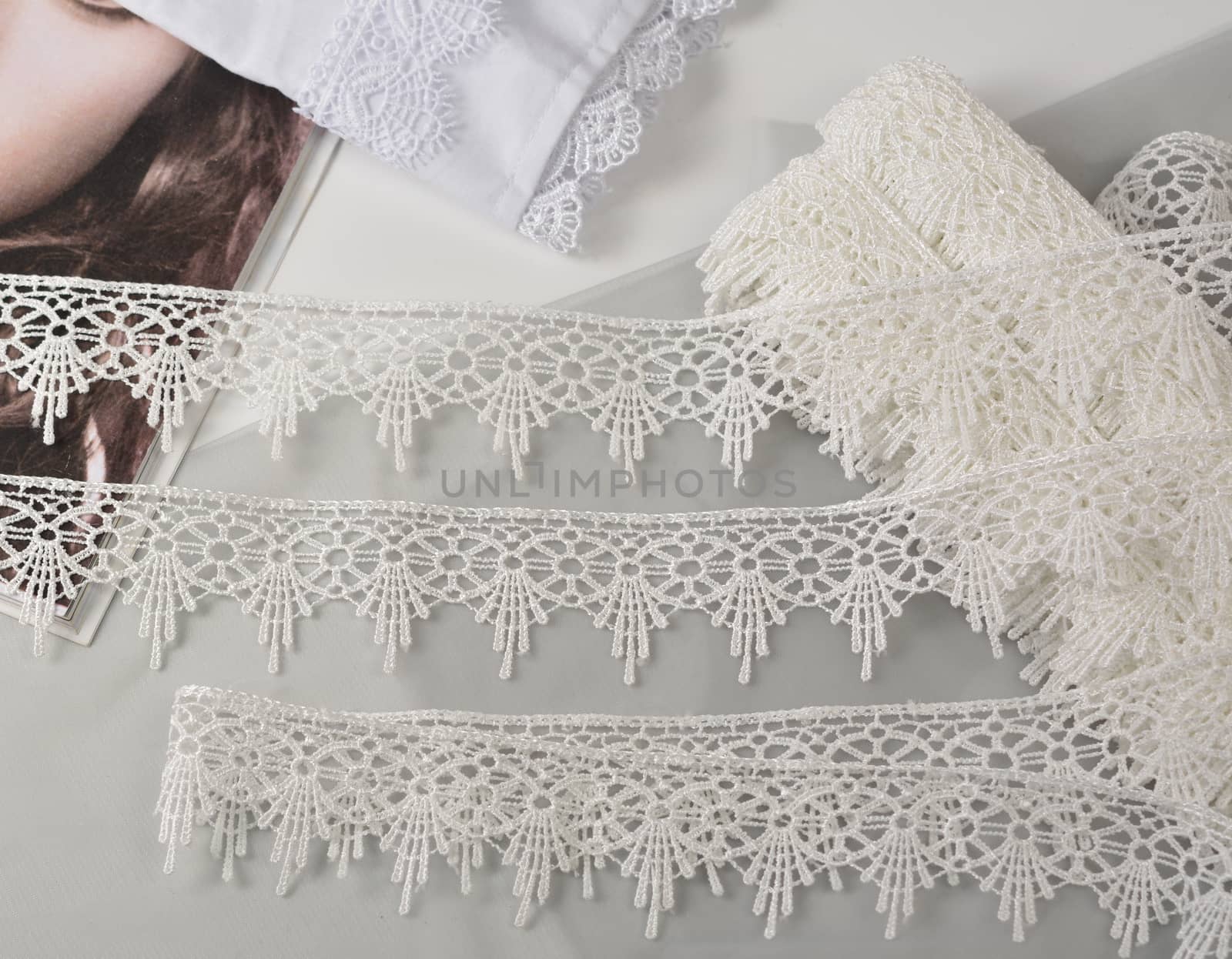 Tapes of ecru white guipure, beauty silk lace fabric on light background. Elastic material. Using for Atelier and needlework store. Flat lay style