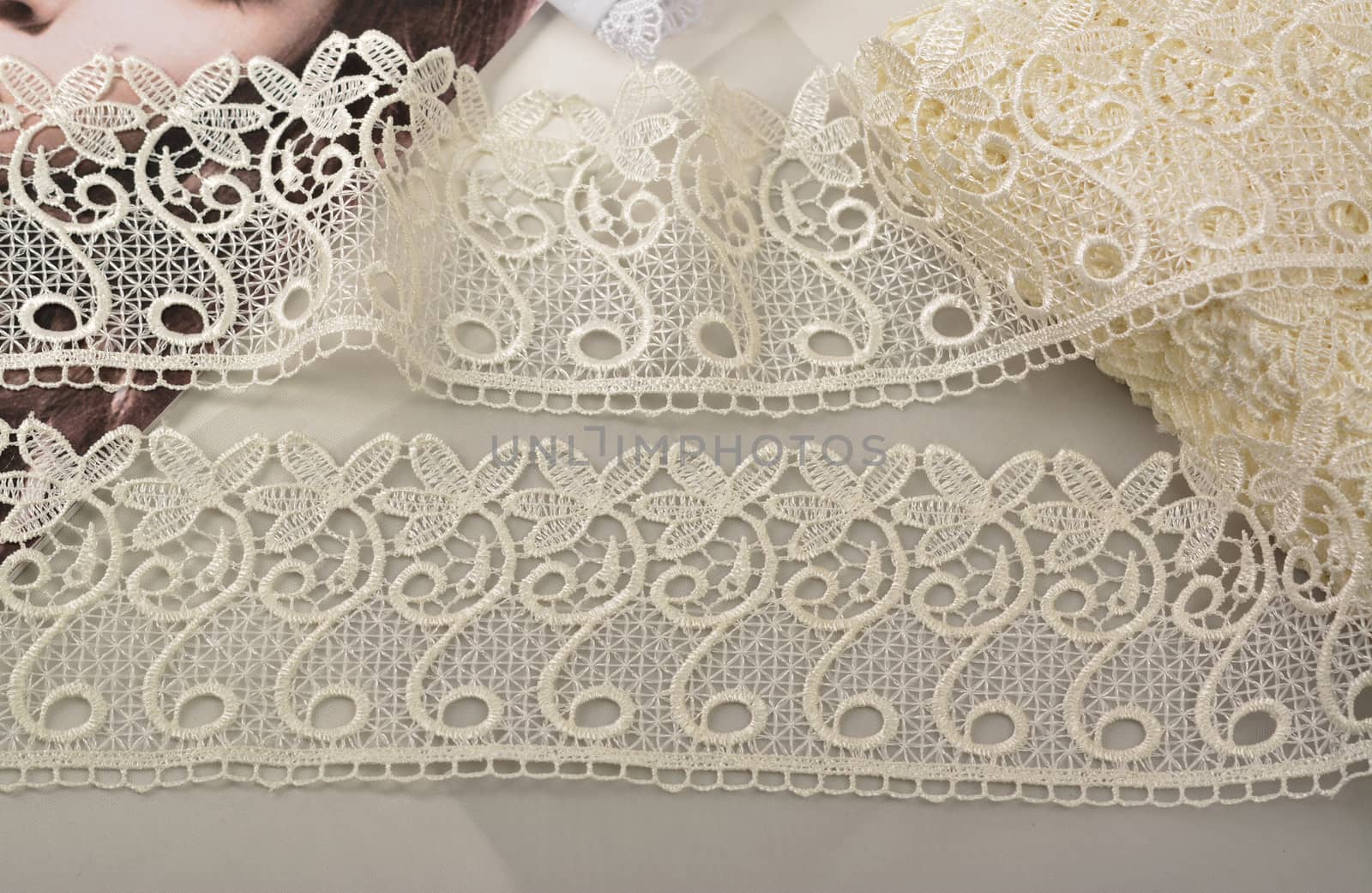 Tapes of ecru white guipure, beauty silk lace fabric on light background. by polyats