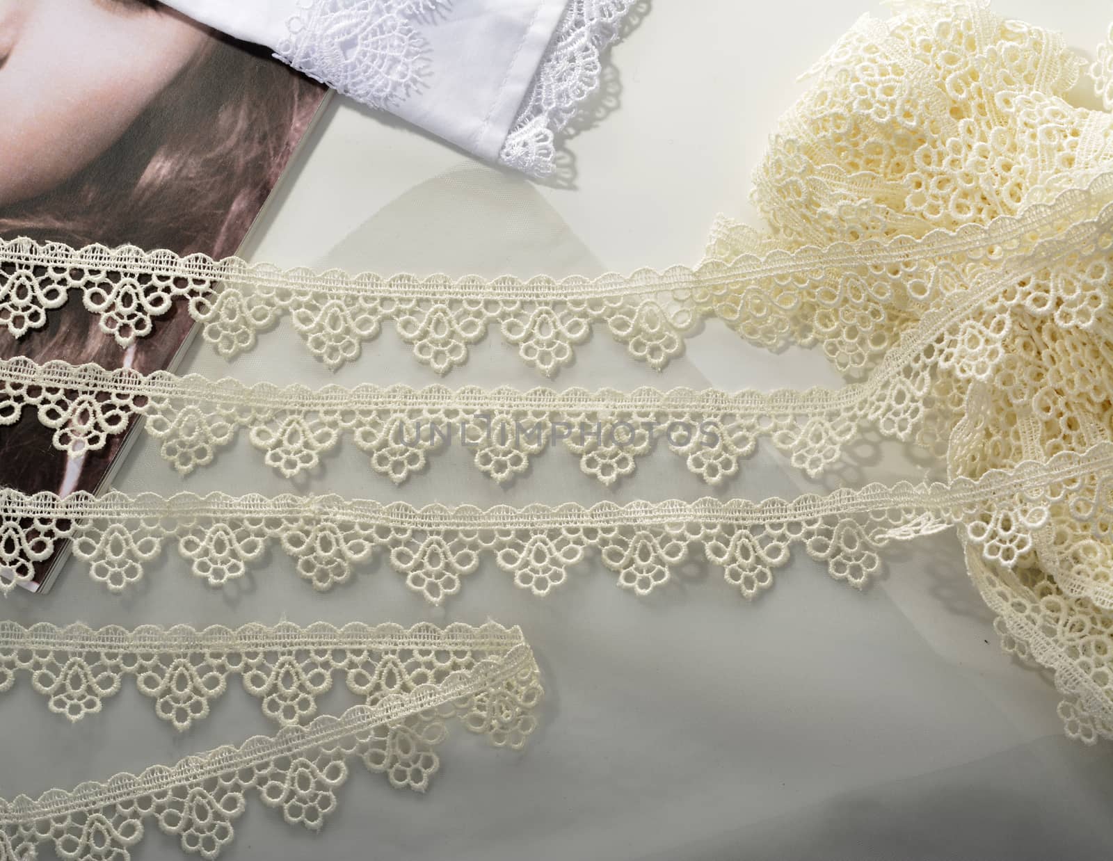 Tapes of ecru white guipure, beauty silk lace fabric on light background. by polyats