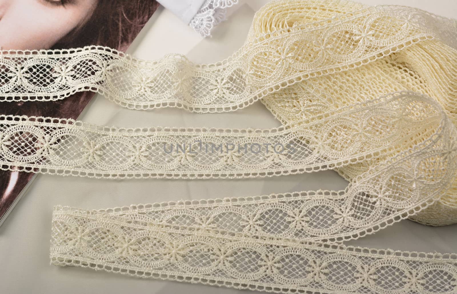 Tapes of ecru white guipure, beauty silk lace fabric on light background. Elastic material. Using for Atelier and needlework store. Flat lay style