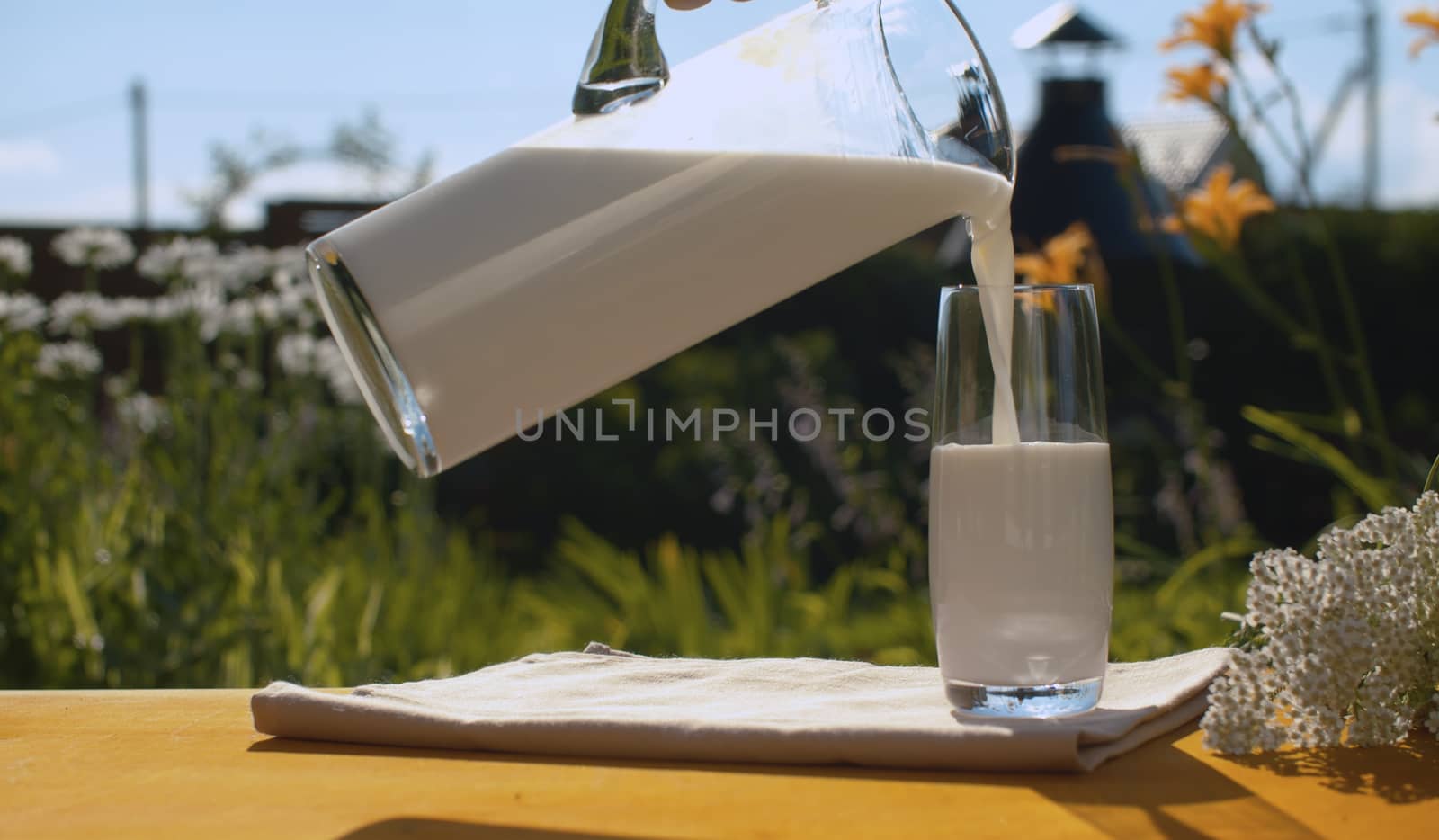 Hand pouring milk into a glass by Alize