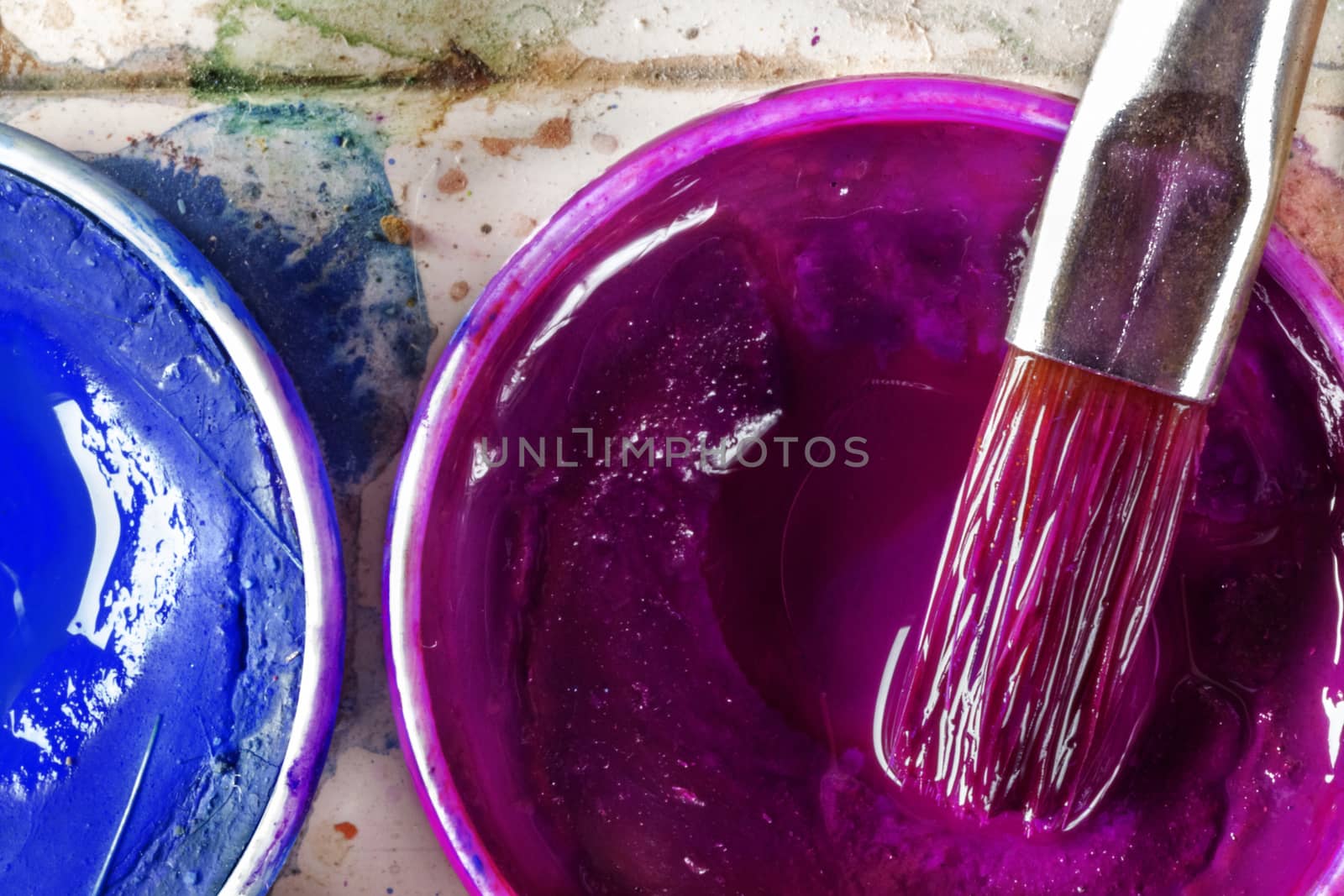 A small set of two watercolors , blue and purple colors in small round bowl ,a paintbrush is on a bowl , top view ,