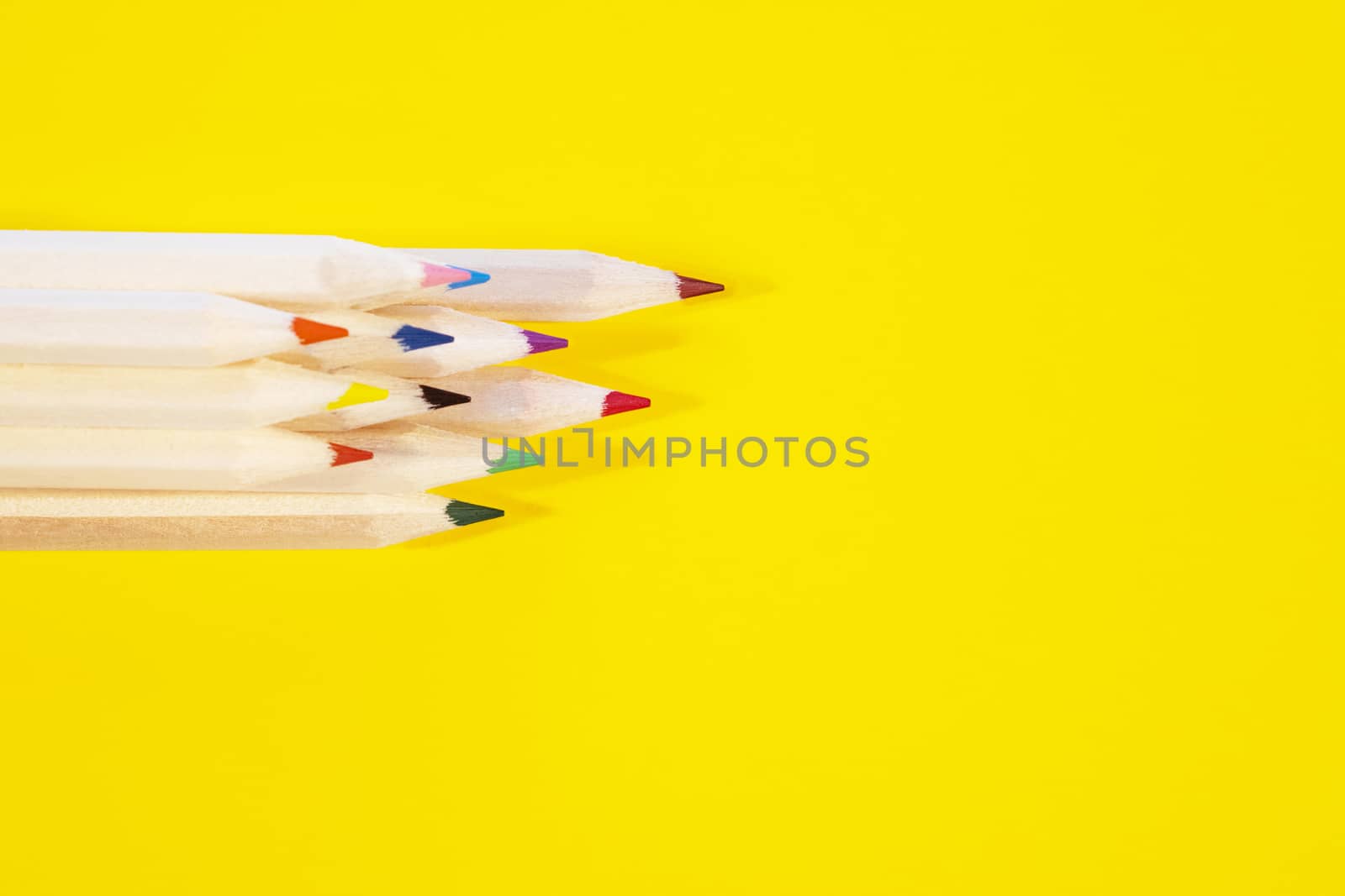 Bunch of wooden color pencils on yellow background ,bright and saturated colors