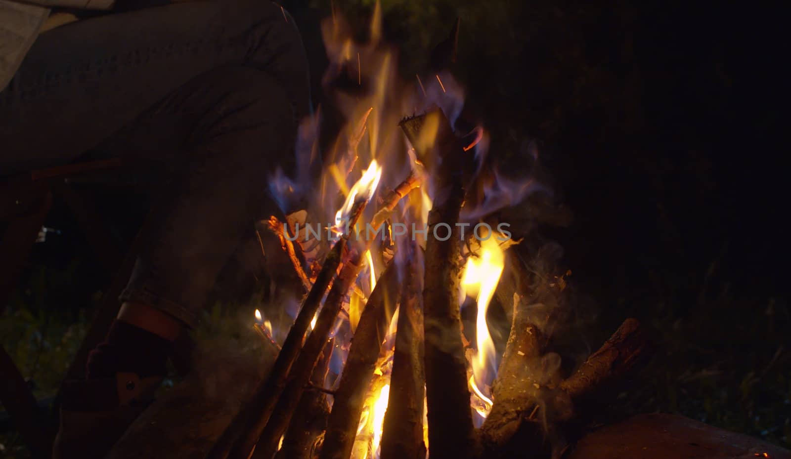 Close up bonfire in the forest at night. Burning woods and stones on the grass glade. Concept of traveling and healthy lifestyle