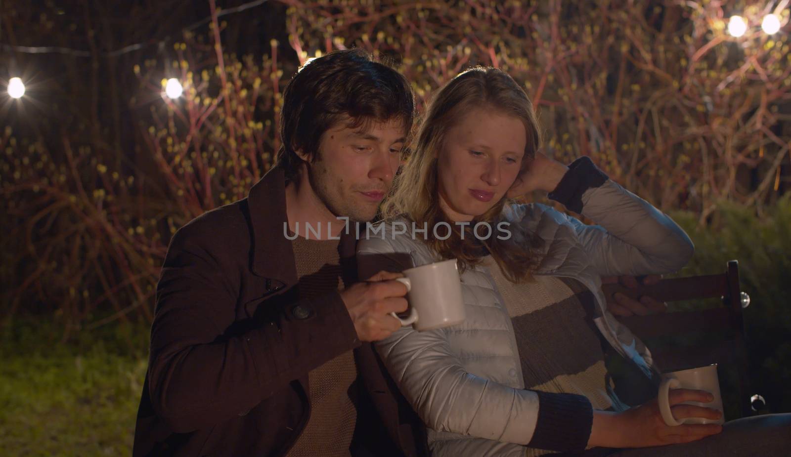 Young happy family at night sitting near bonfire and hugging. Couple on weekend in the forest. Healthy lifestyle concept