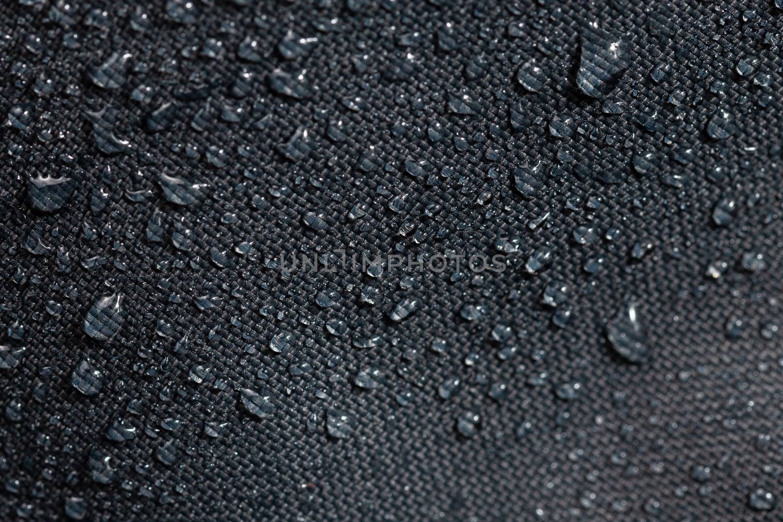 dark gray waterproof hydrophobic cloth closeup with water drops selective focus background.