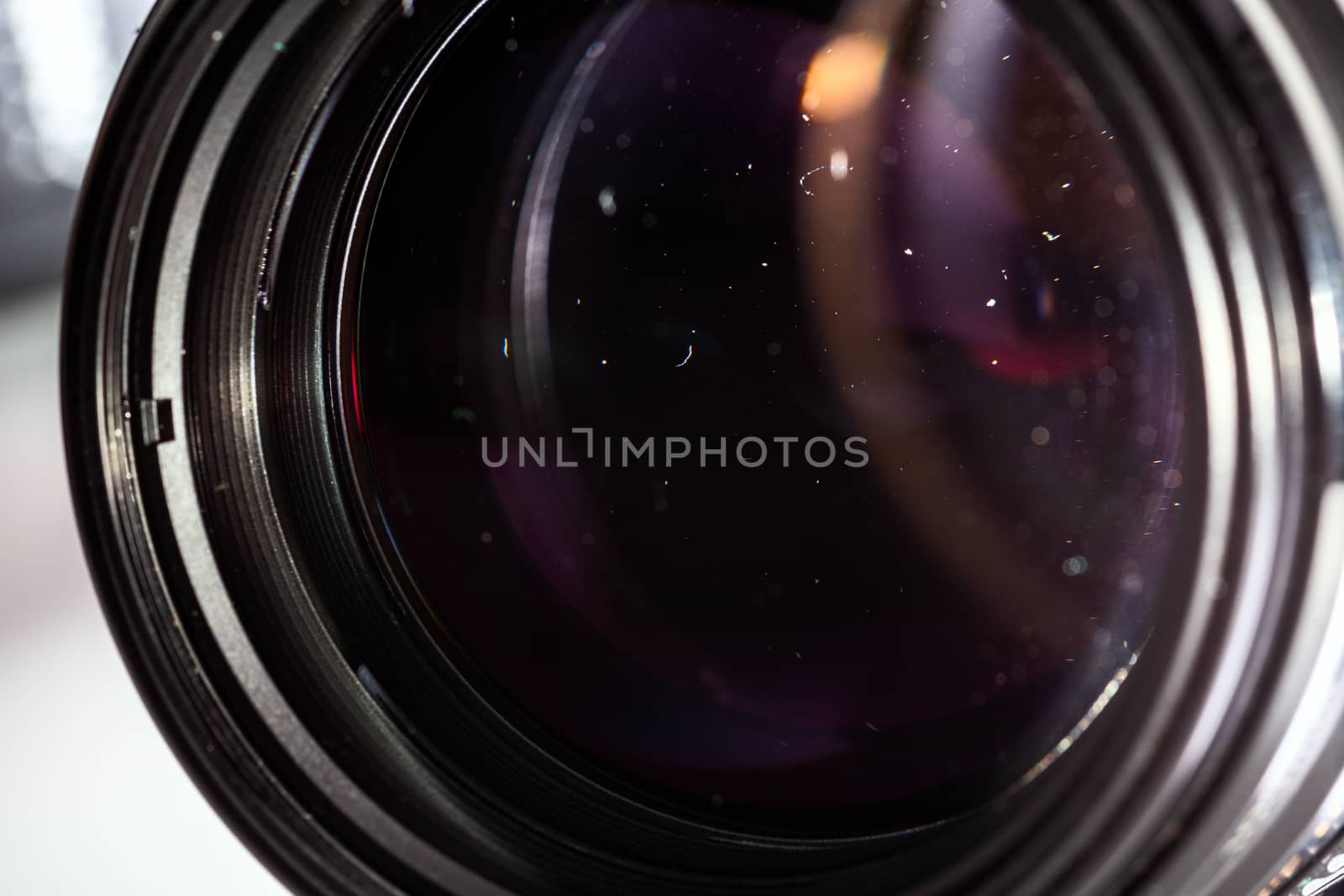 Dust particles in camera lens closeup shot with selective focus and blur. Large front element of professional objective.