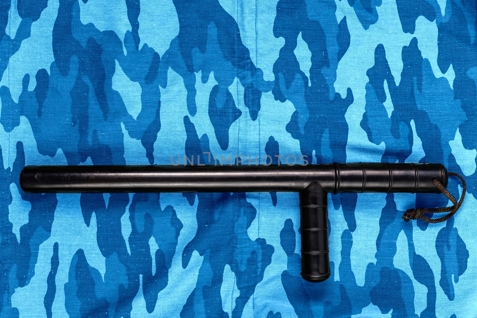 black rubber baton on blue urban russian riot police camouflage flat lay top-down perspective.