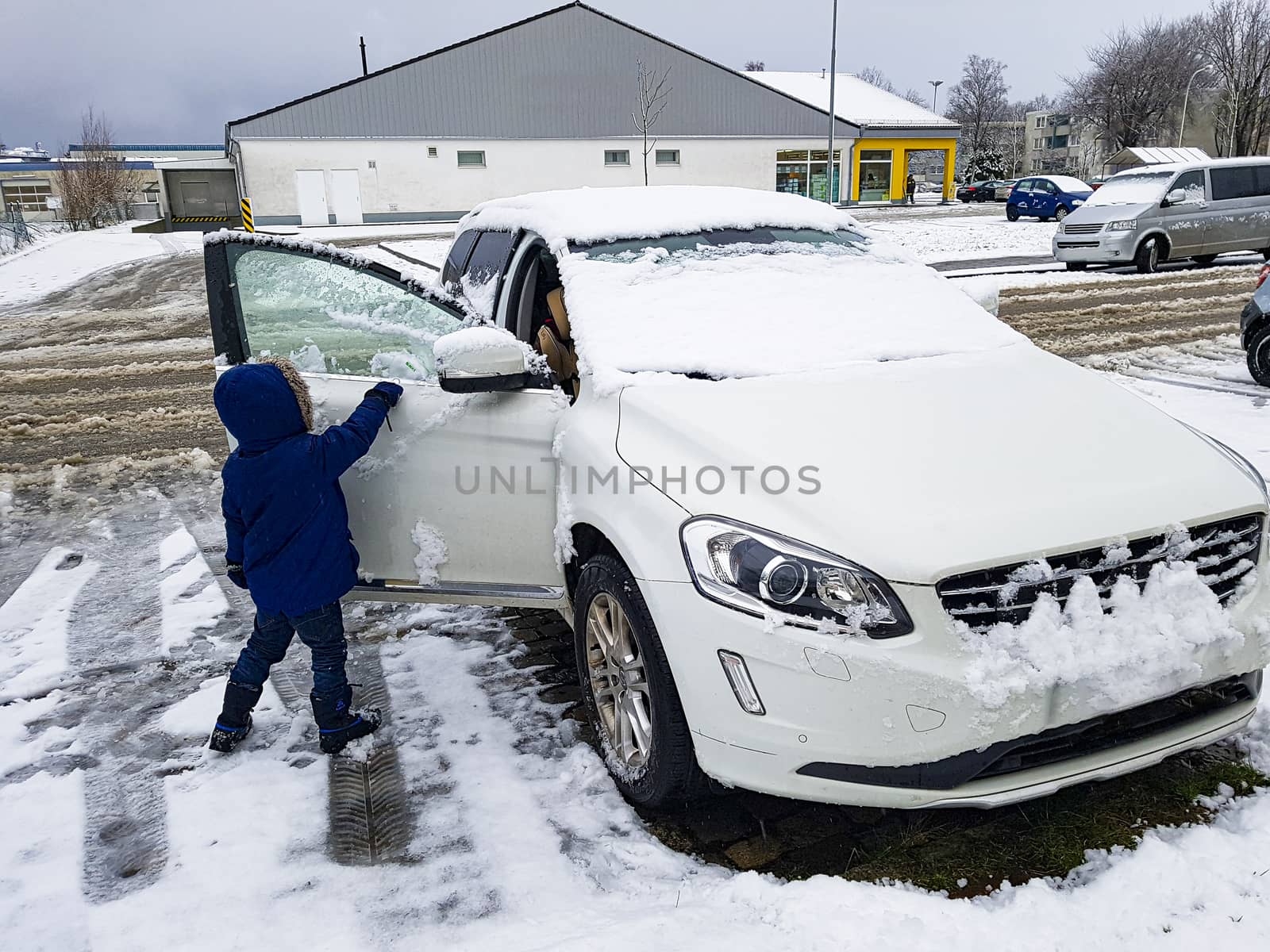 Child frees car from snow and ice in Germany. by Arkadij