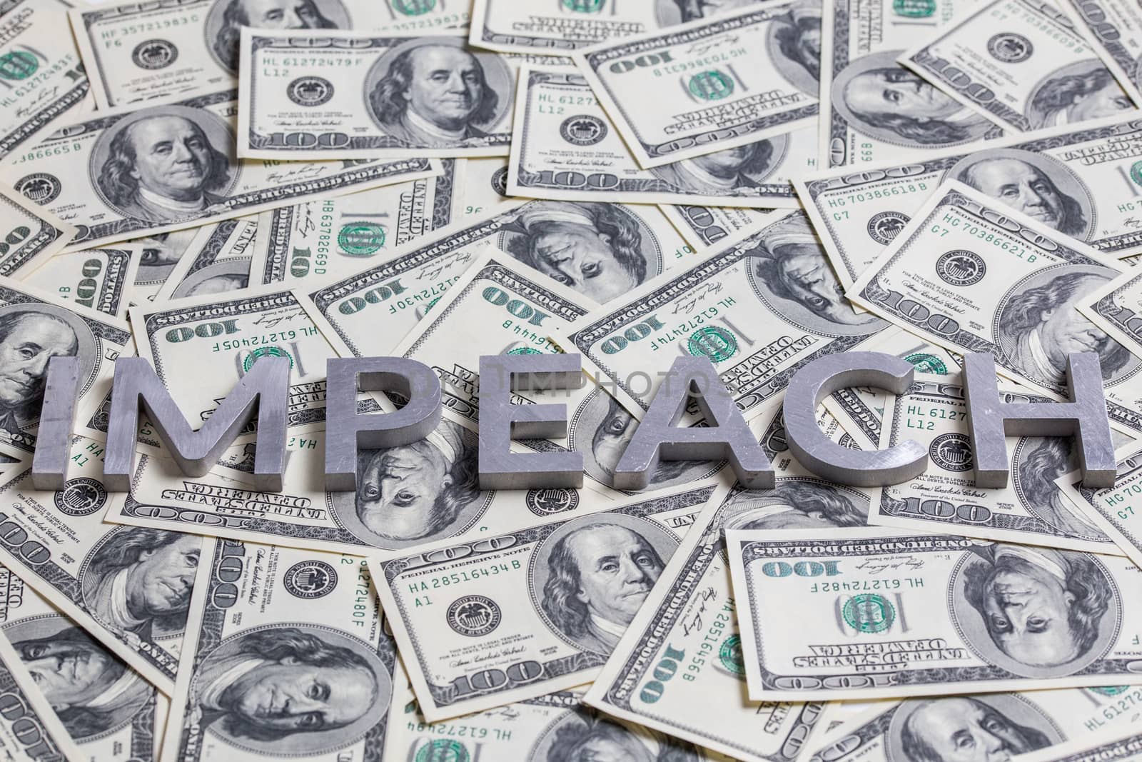 The word IMPEACH laid with aluminium letters on the US dollar banknotes background - with selective focus and diagonal composition.