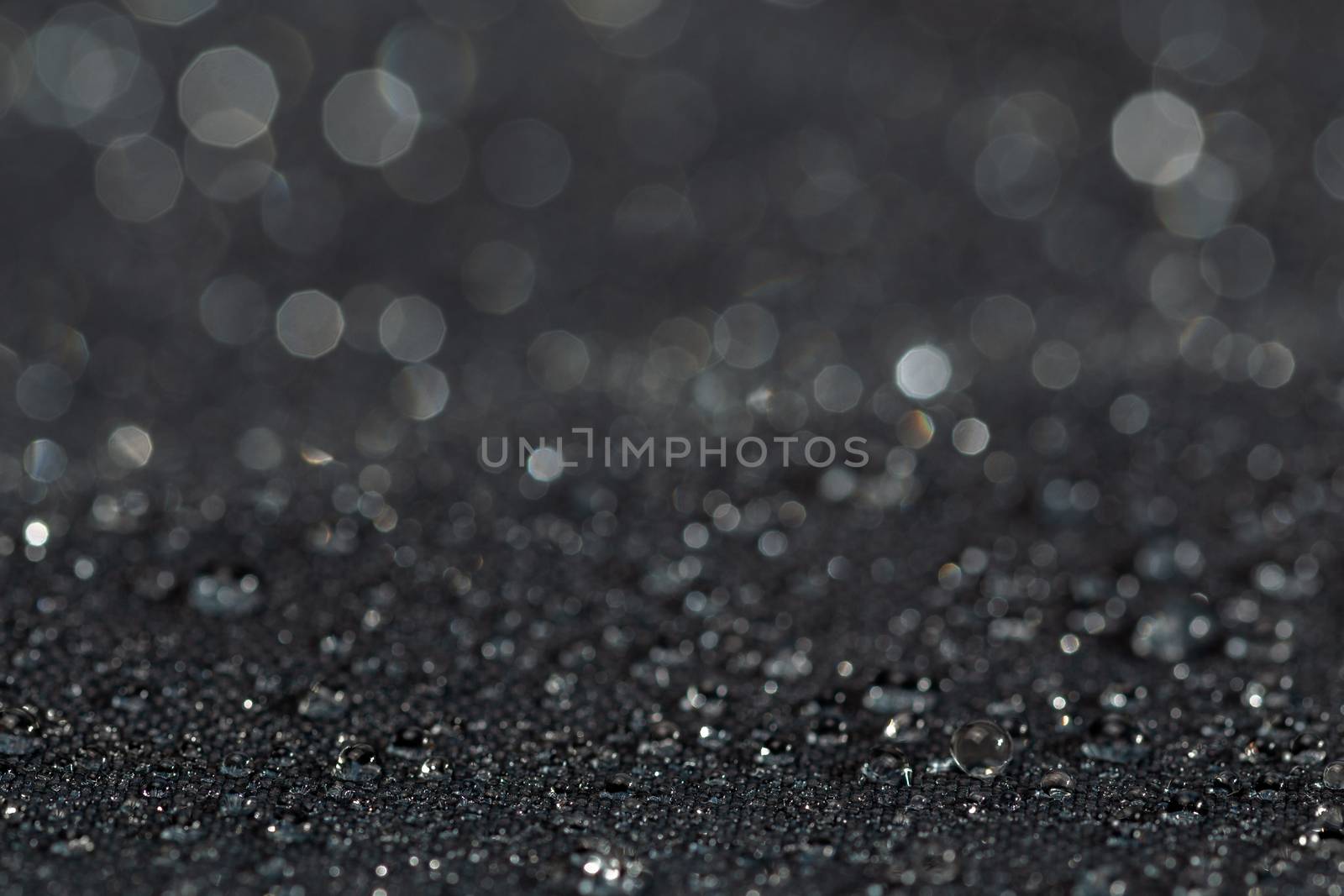 dark gray waterproof hydrophobic flat cloth closeup with water drops selective focus background.