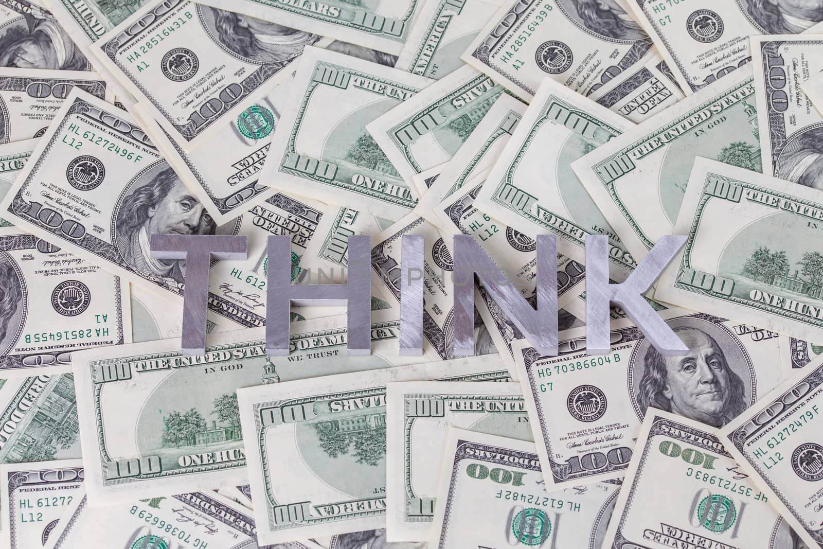 The word THINK laid with aluminium letters on the US dollar banknotes background - with selective focus and blur.