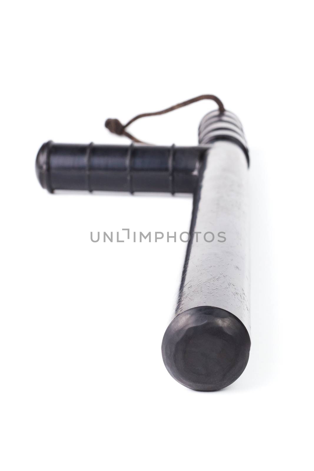 Black classic rubber police tonfa baton isolated on white background with selective focus and wide angle perspective.