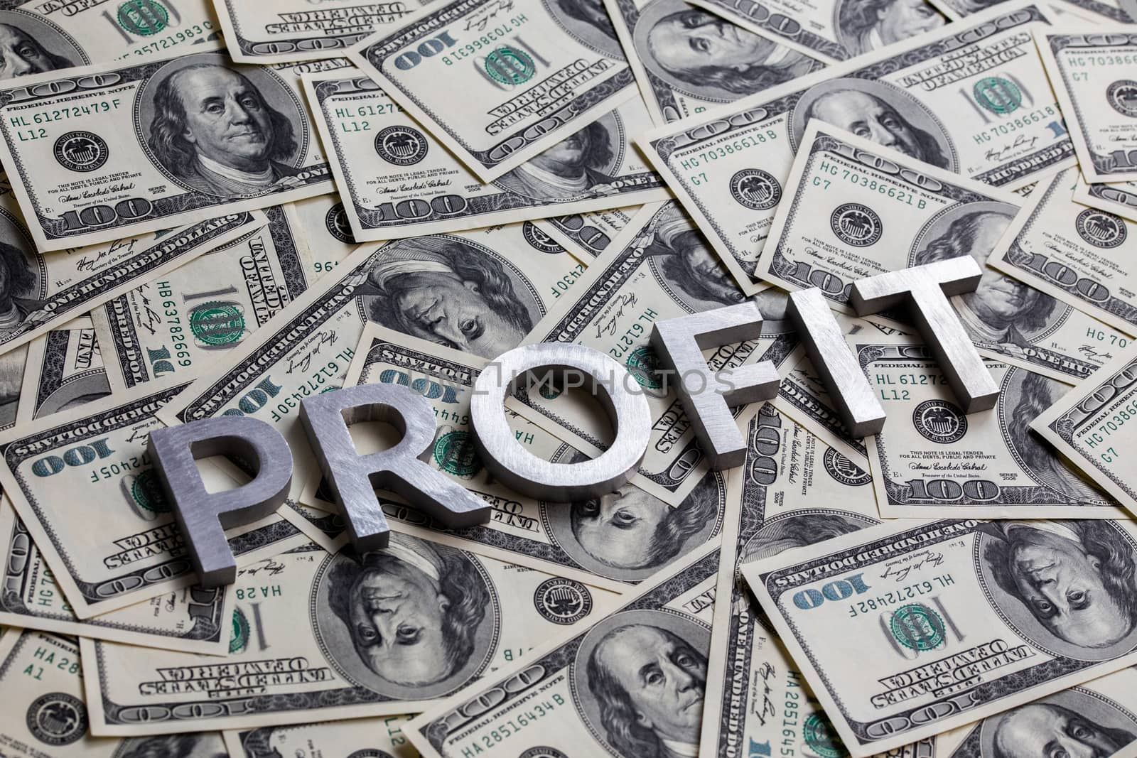 The word PROFIT laid with aluminium letters on the US dollar banknotes background - with selective focus and diagonal composition.