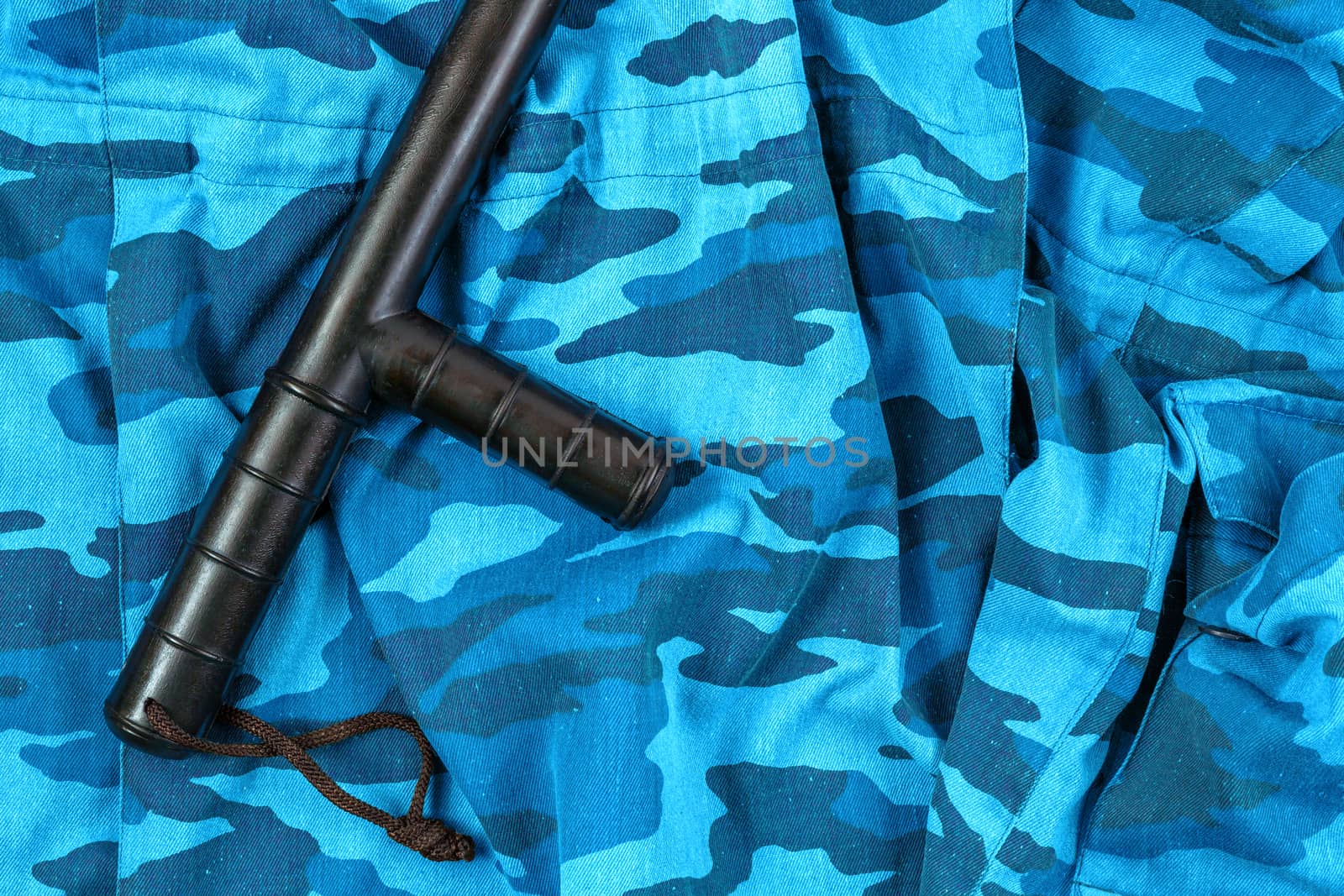 black rubber baton on blue urban russian riot police camouflage flat lay top-down perspective.