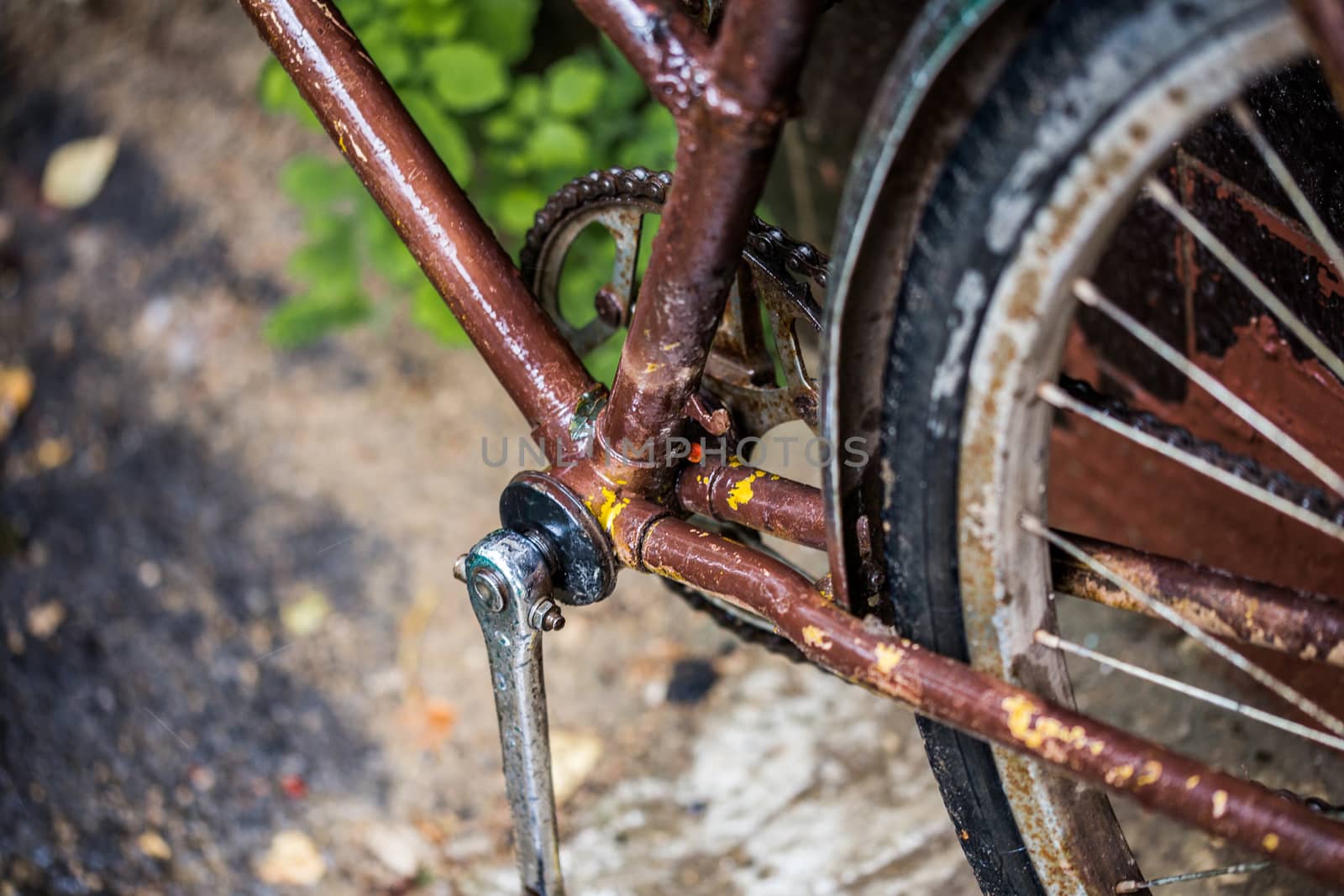old rused brown bicycle closeup with selective focus and blur after rain.