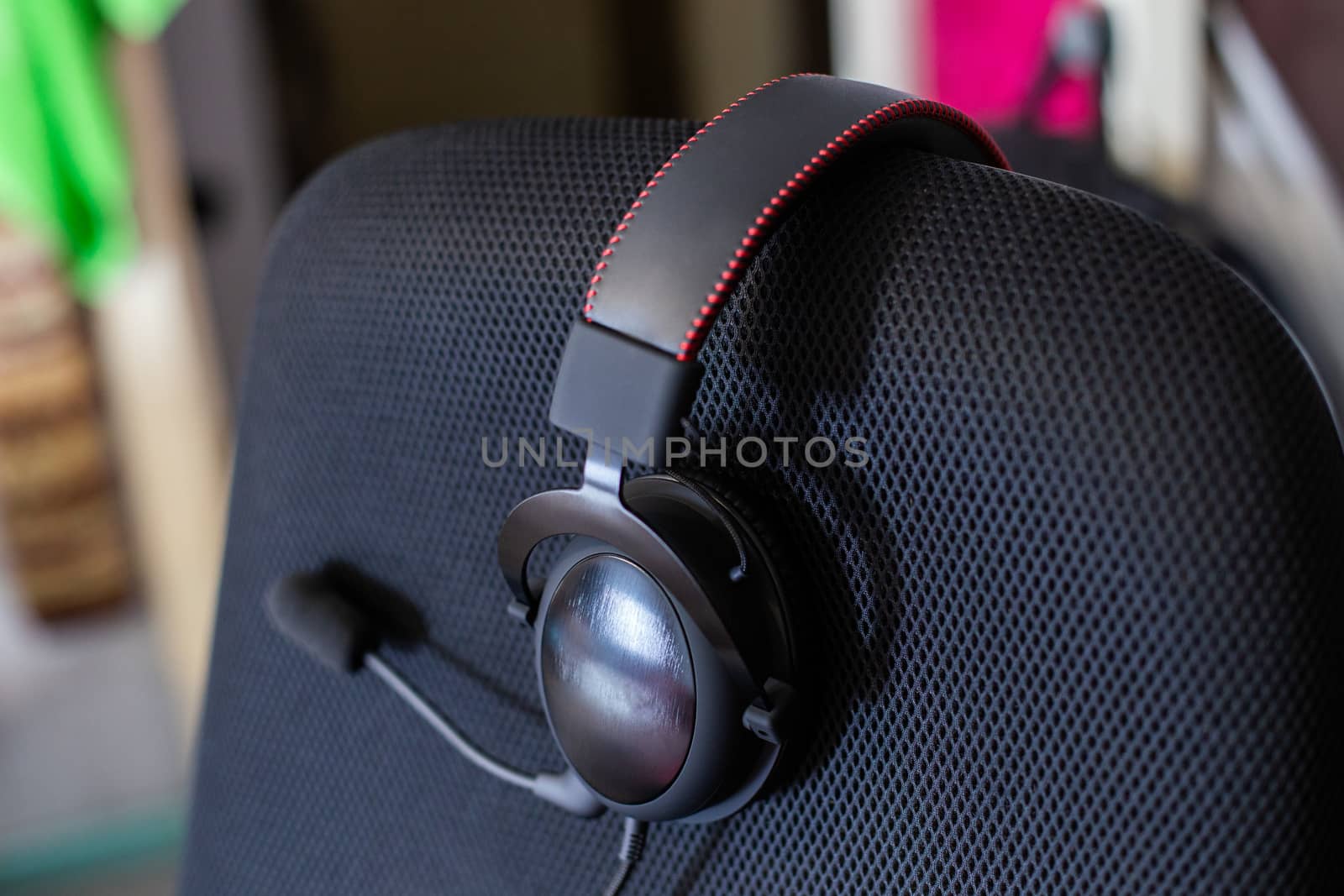 black headset on backrest of empty computer chair with air mesh upholstery.