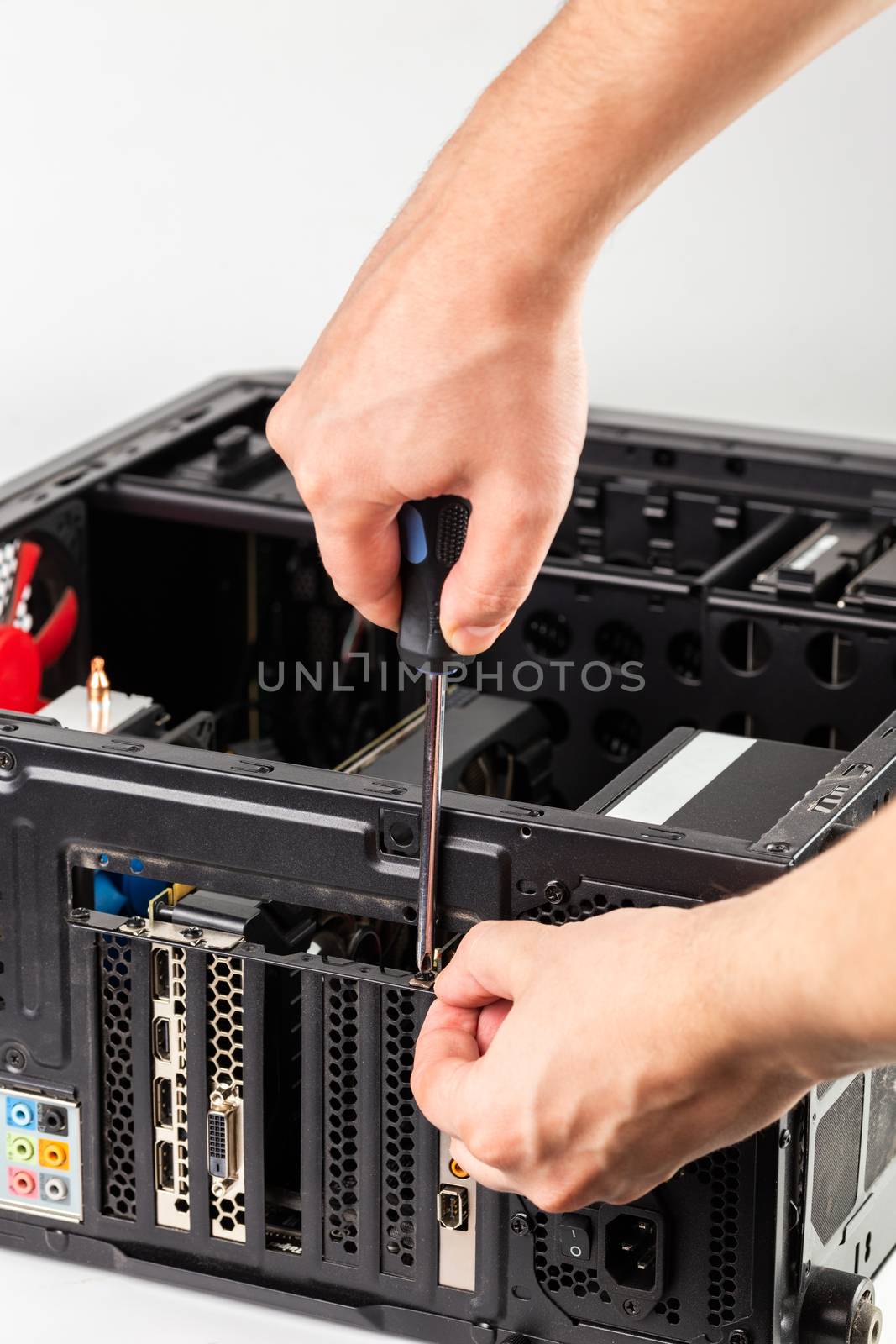 hands unscrewing a video card bracket while maintenance personal computer hardware with selective focus closeup