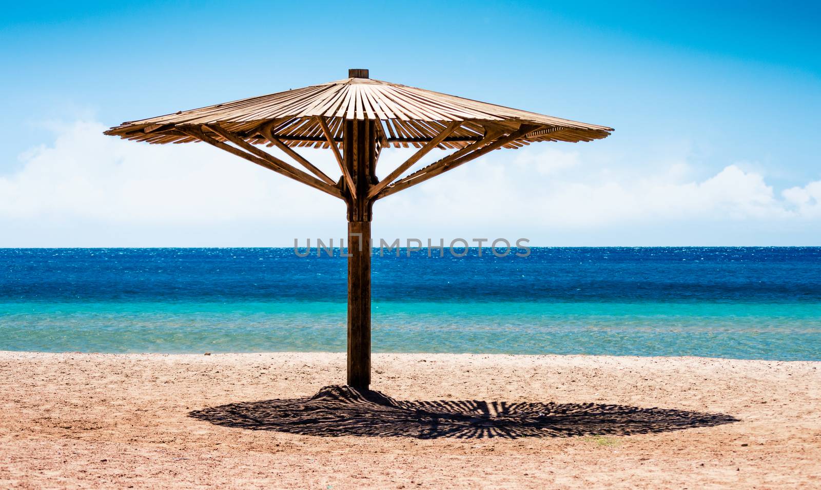 wooden beach umbrella on the shore without people of the Red Sea by Gera8th