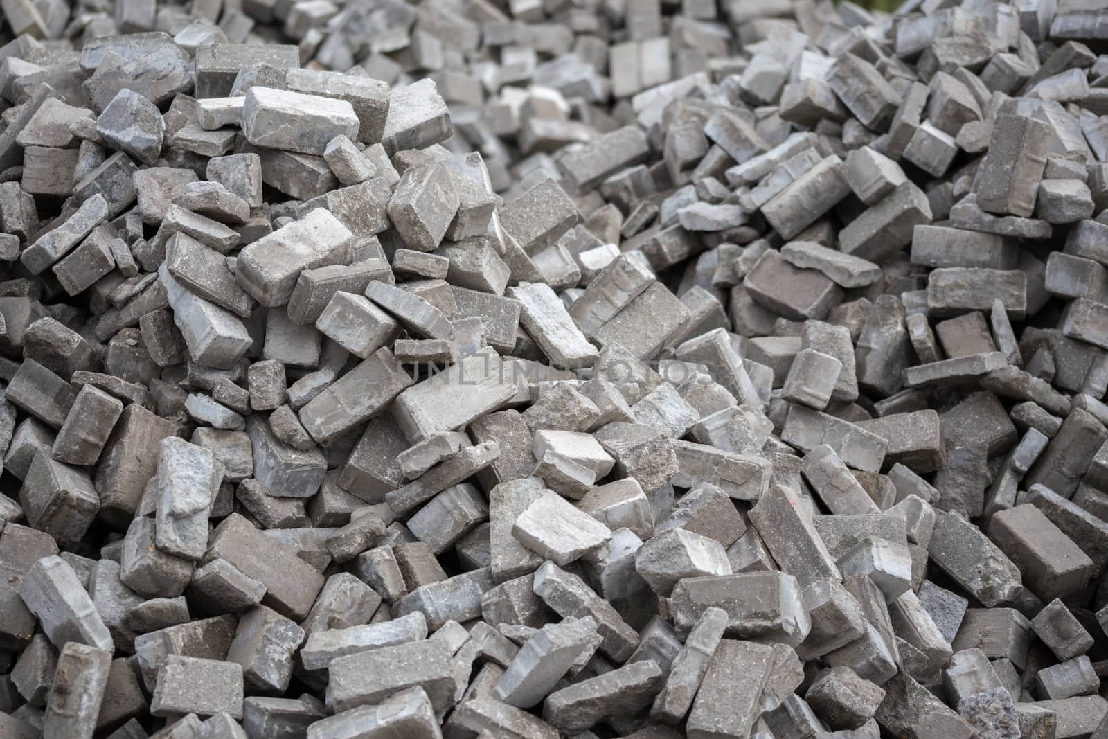 Pile of dismounted gray modern urban pavement bricks with selective focus. Result of russian government corruption in city infrastructure renovation. Piles hidden outside of city - in suburbs wasteland.